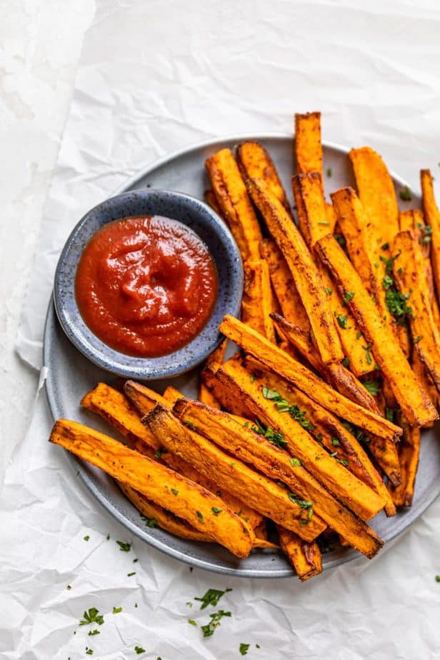 sweet potato fries on dark plate with red dipping sauce
