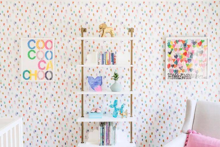 multicolored polkadot wallpaper with white bookshelf and posters on wall