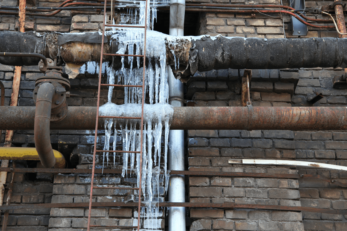 broken pipes on brick building with frozen water