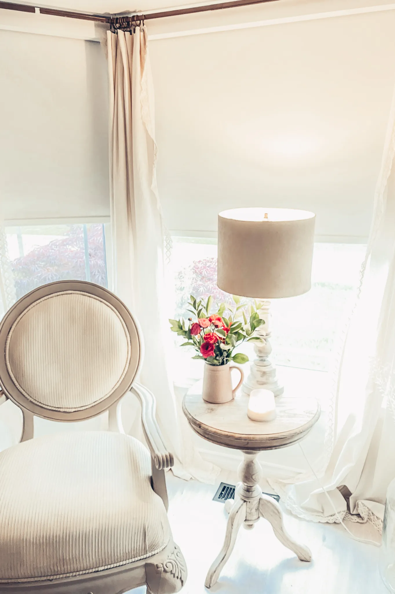 white vintage wood fabric chair positioned at window next to vintage stool table and lamp