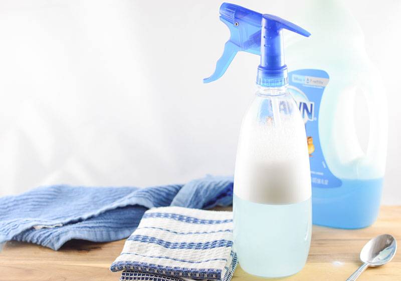 spray bottle full of cleaning solution with dish towel, spoon, and dawn dish soap on counter