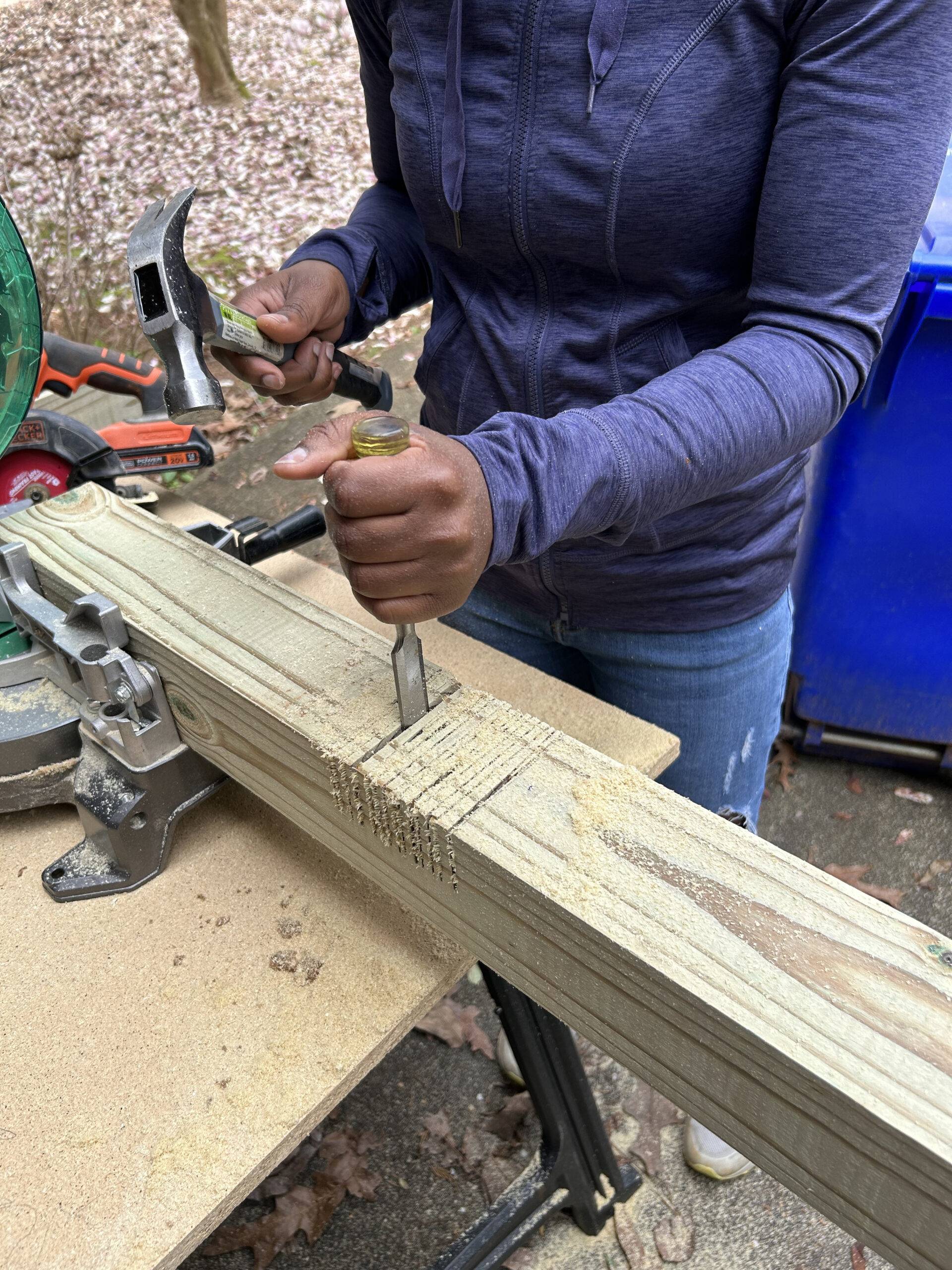 using a chisel to notch out piece of wood from post