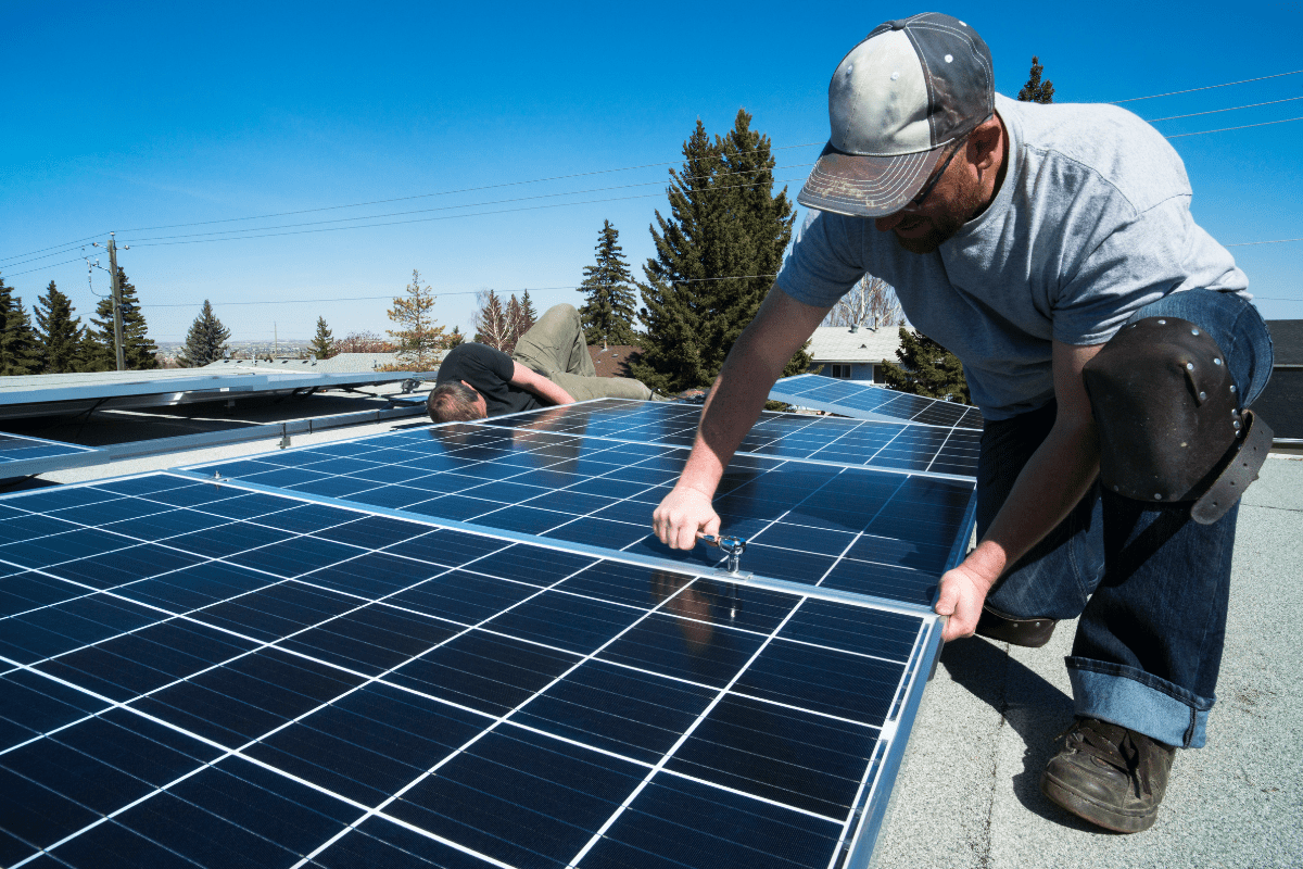 man on rough installing solar panels on bright clear day
