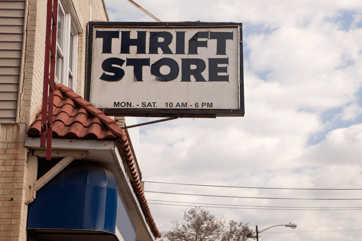 thrift store signage with big black lettering against cloudy sky