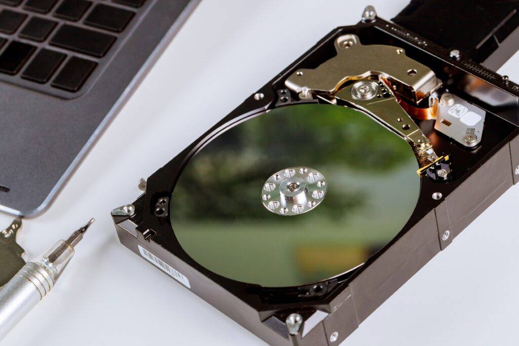 inside look at hard drive disk without cover on it on desk next to laptop