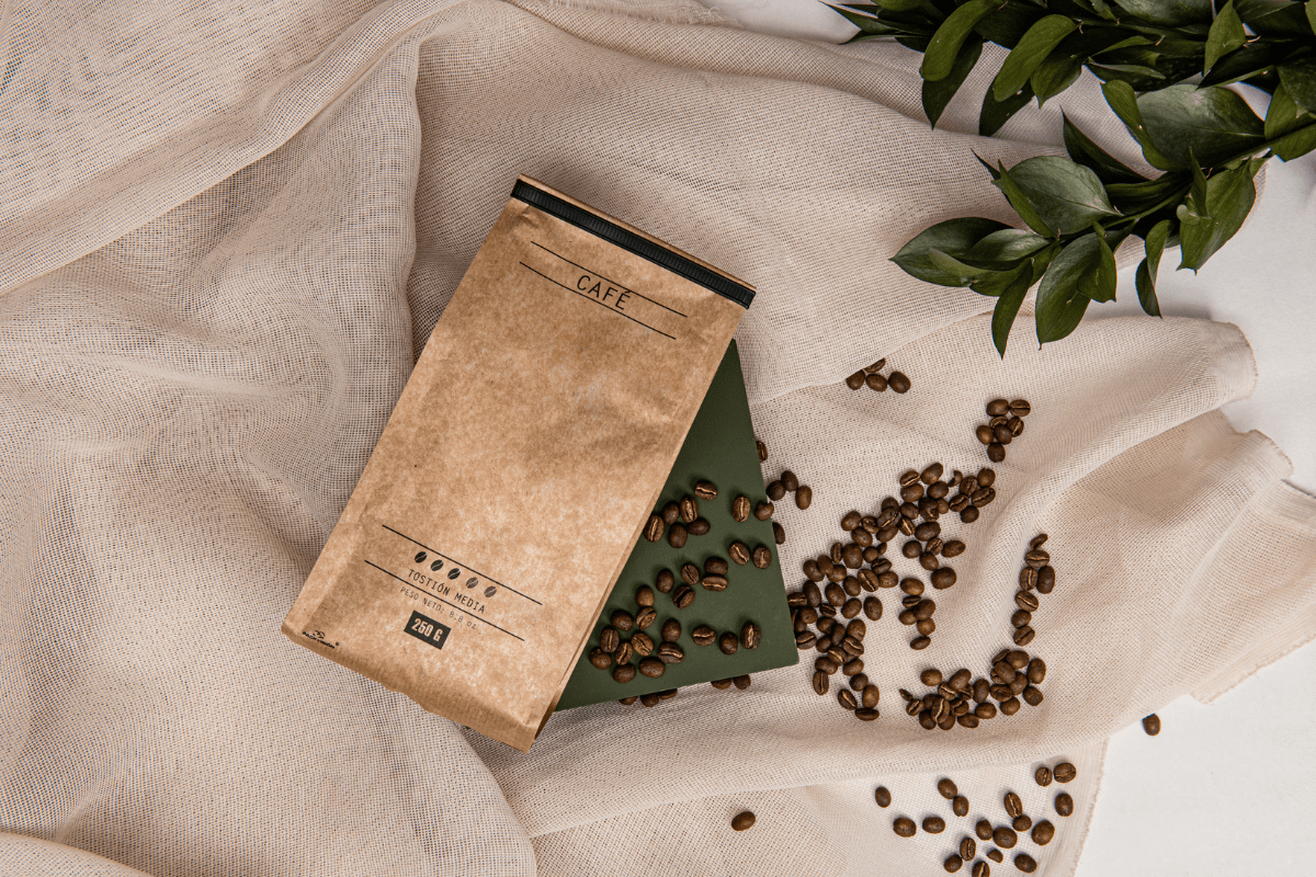 flatlay of brown paper bag of coffee beans spilling onto burlap