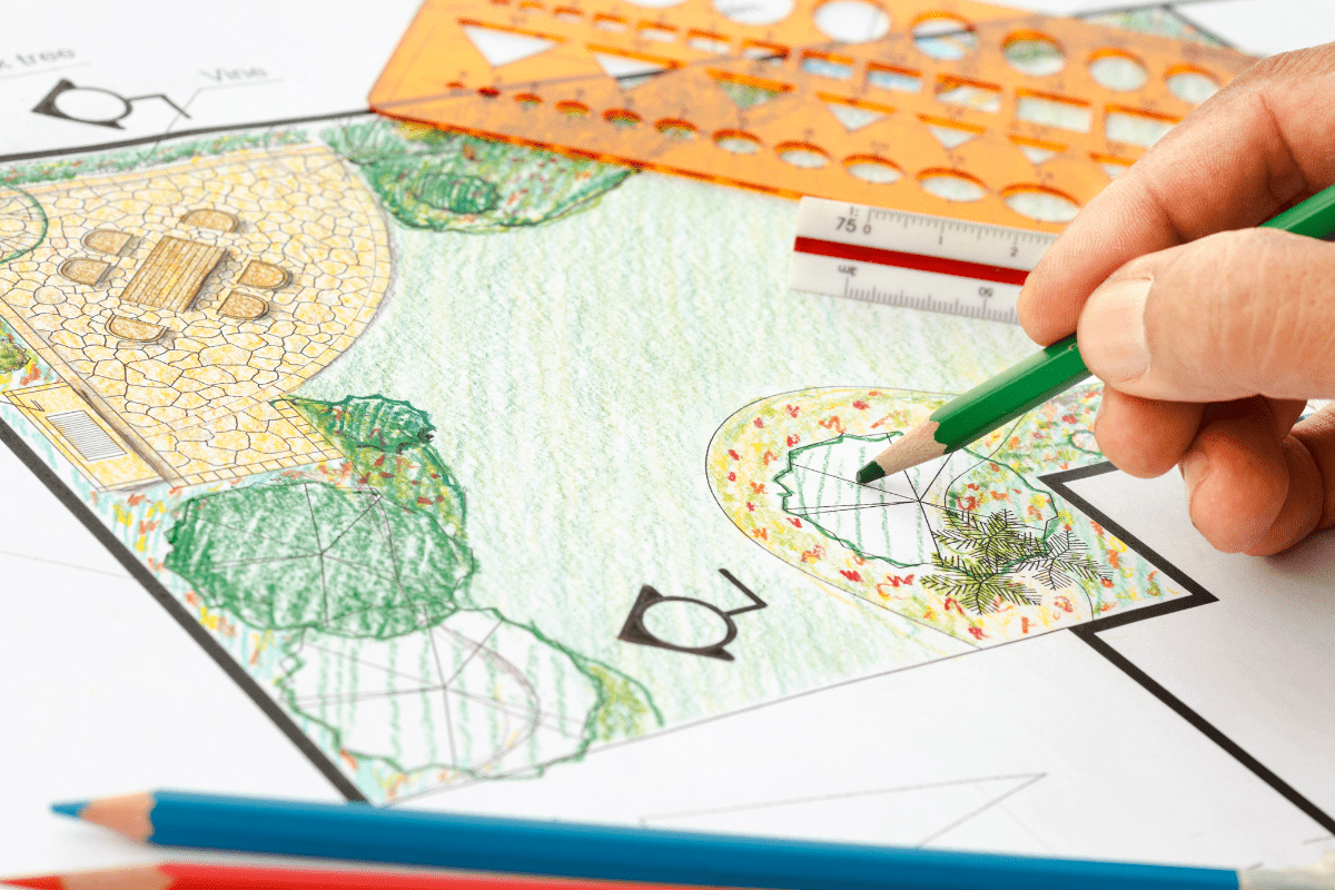 close up of man holding green pencil crayon, drawing design of landscaping project