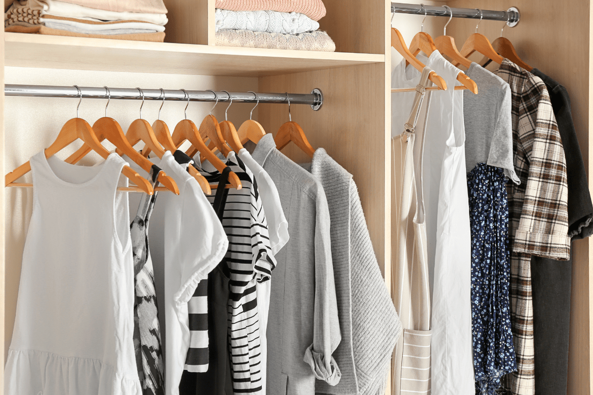 close up of clothes hanging in closet on wood hangers