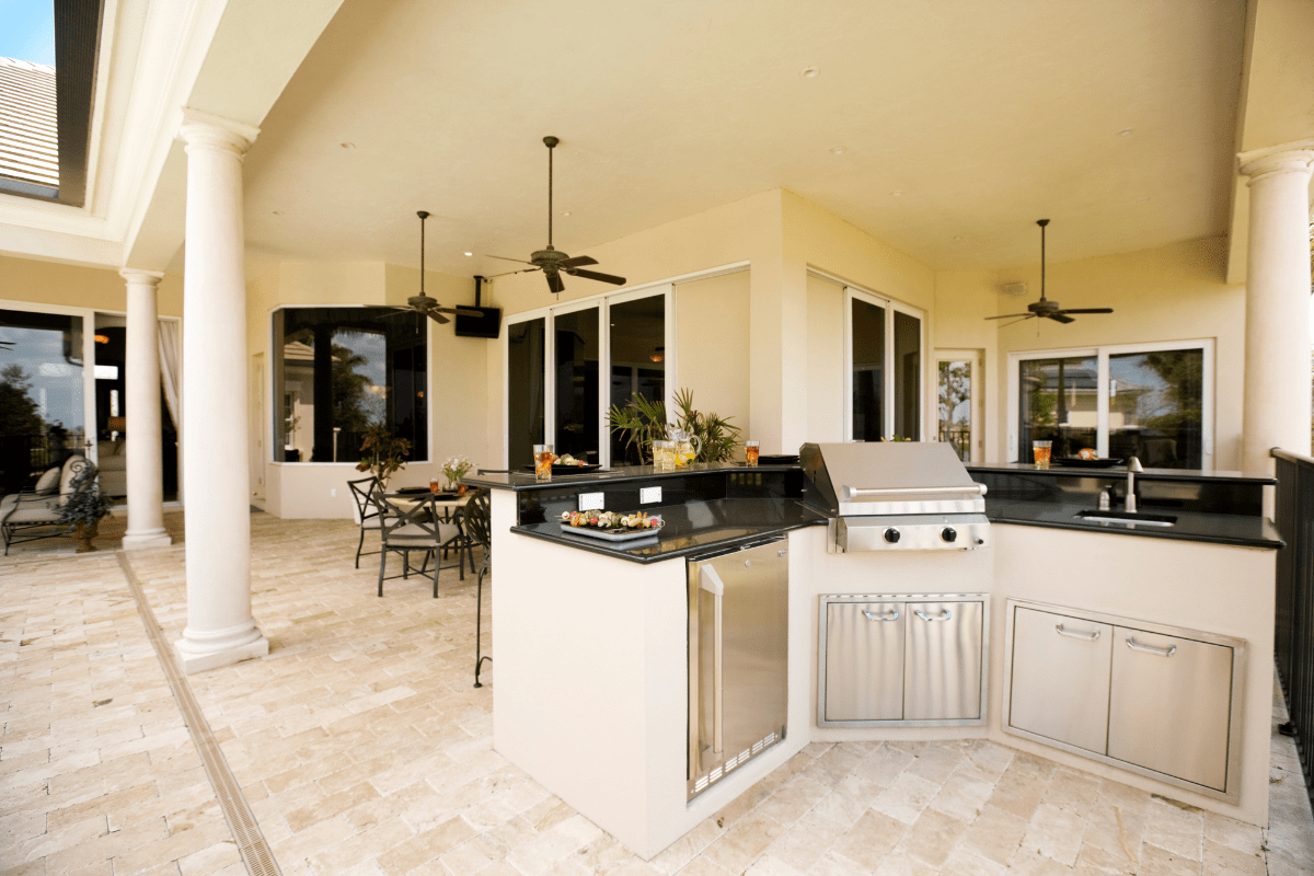 large white outdoor kitchen on covred patio with fans