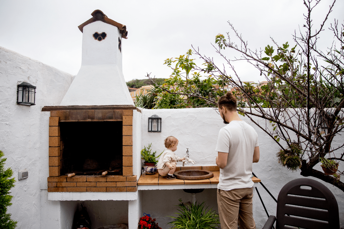 man cooking in outdoor kitchen with small child