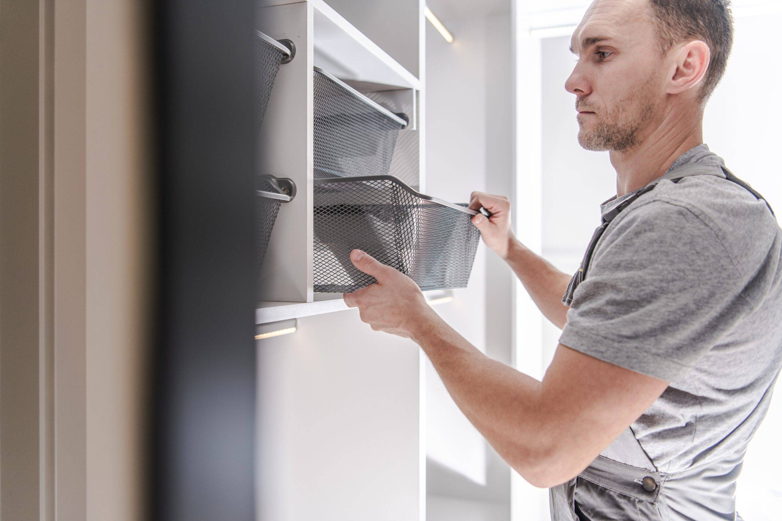 adult male adding storage bins to closet shelves