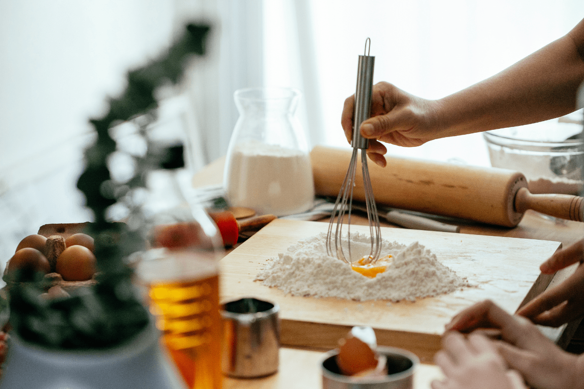 close up of someone using a whisk with egg and flour on cutting board