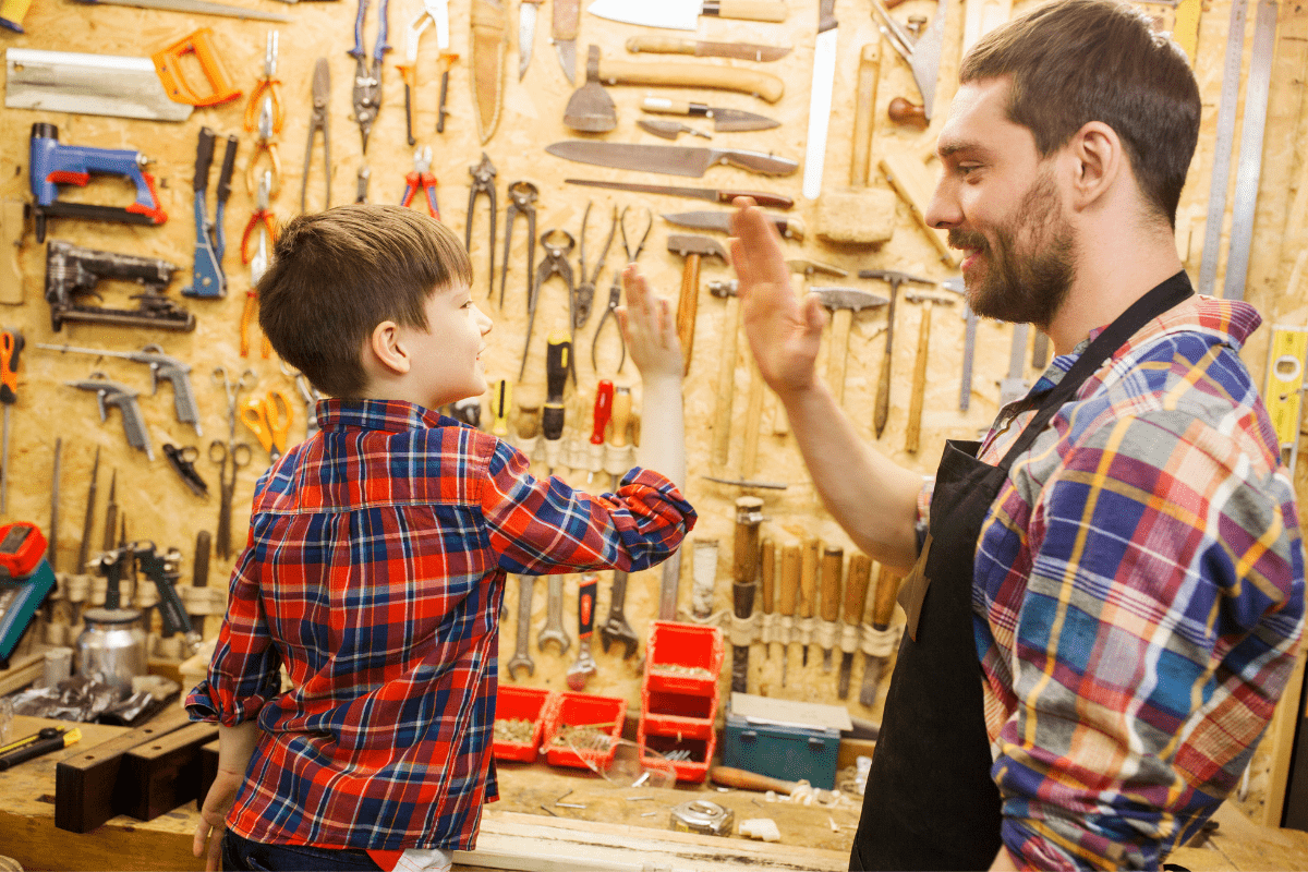 father and son woodworking high five in workshop
