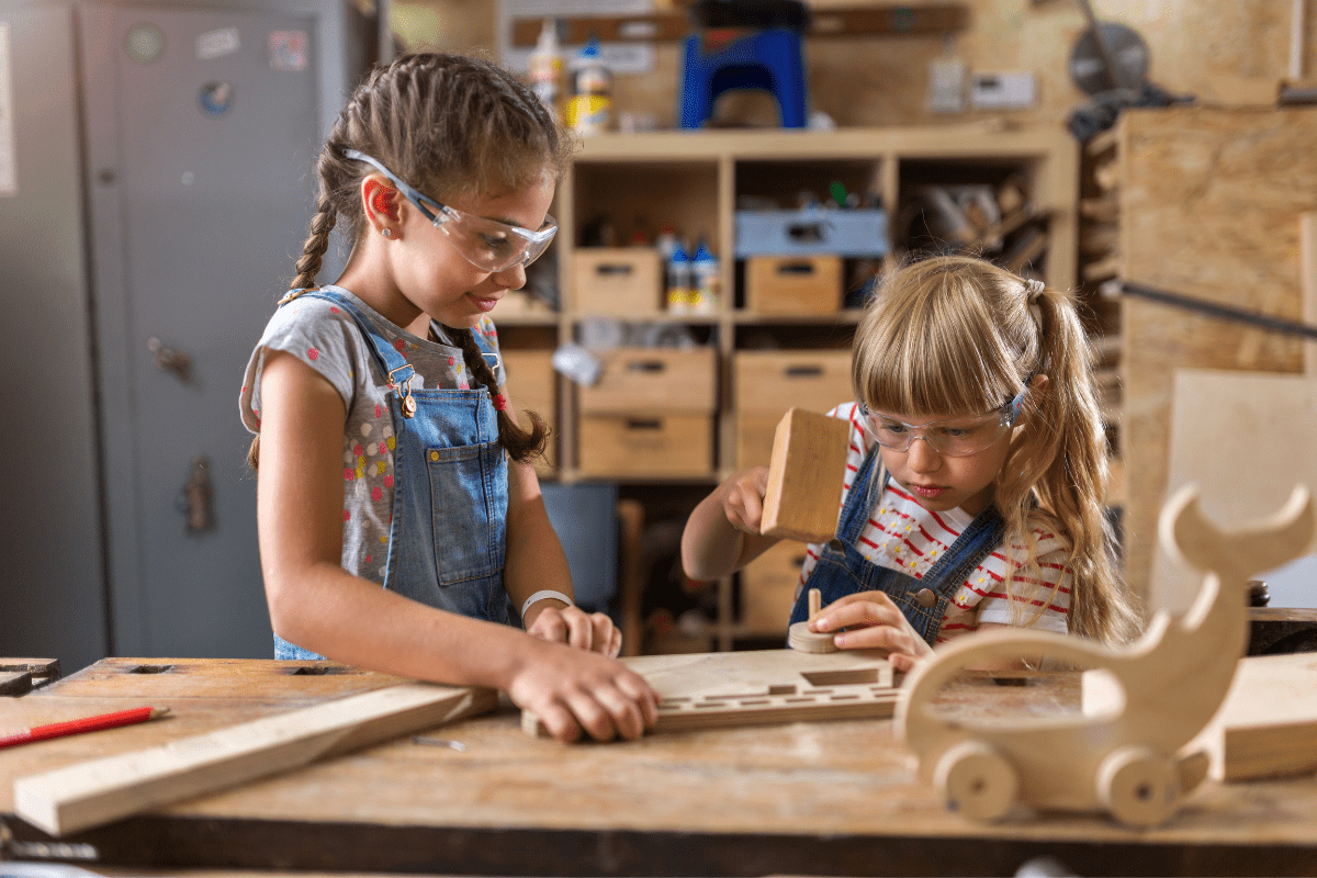 two girls wearing safety glasses working on wood projects crafts