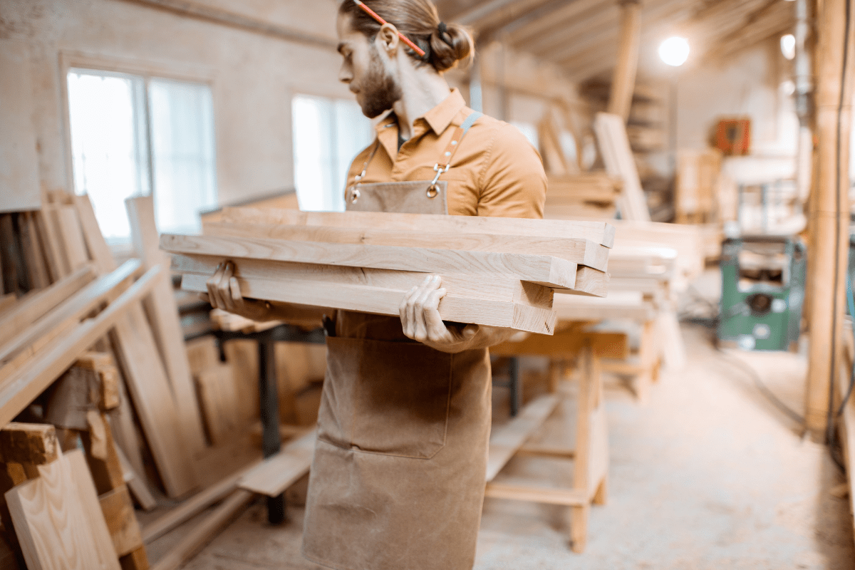 Carpenter carrying pine planks in the warehosue