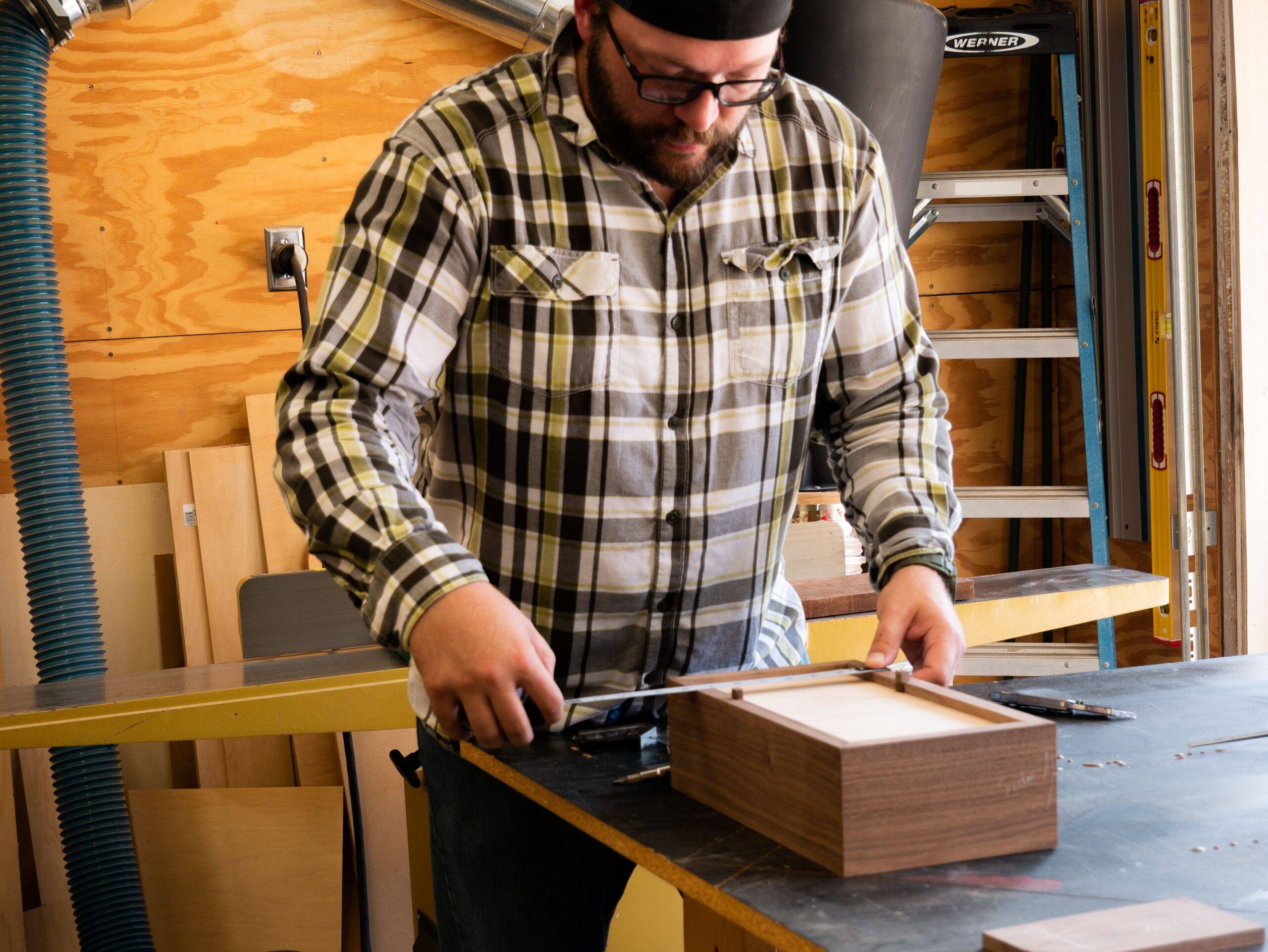 A carpenter measuring out the next steps in his box build