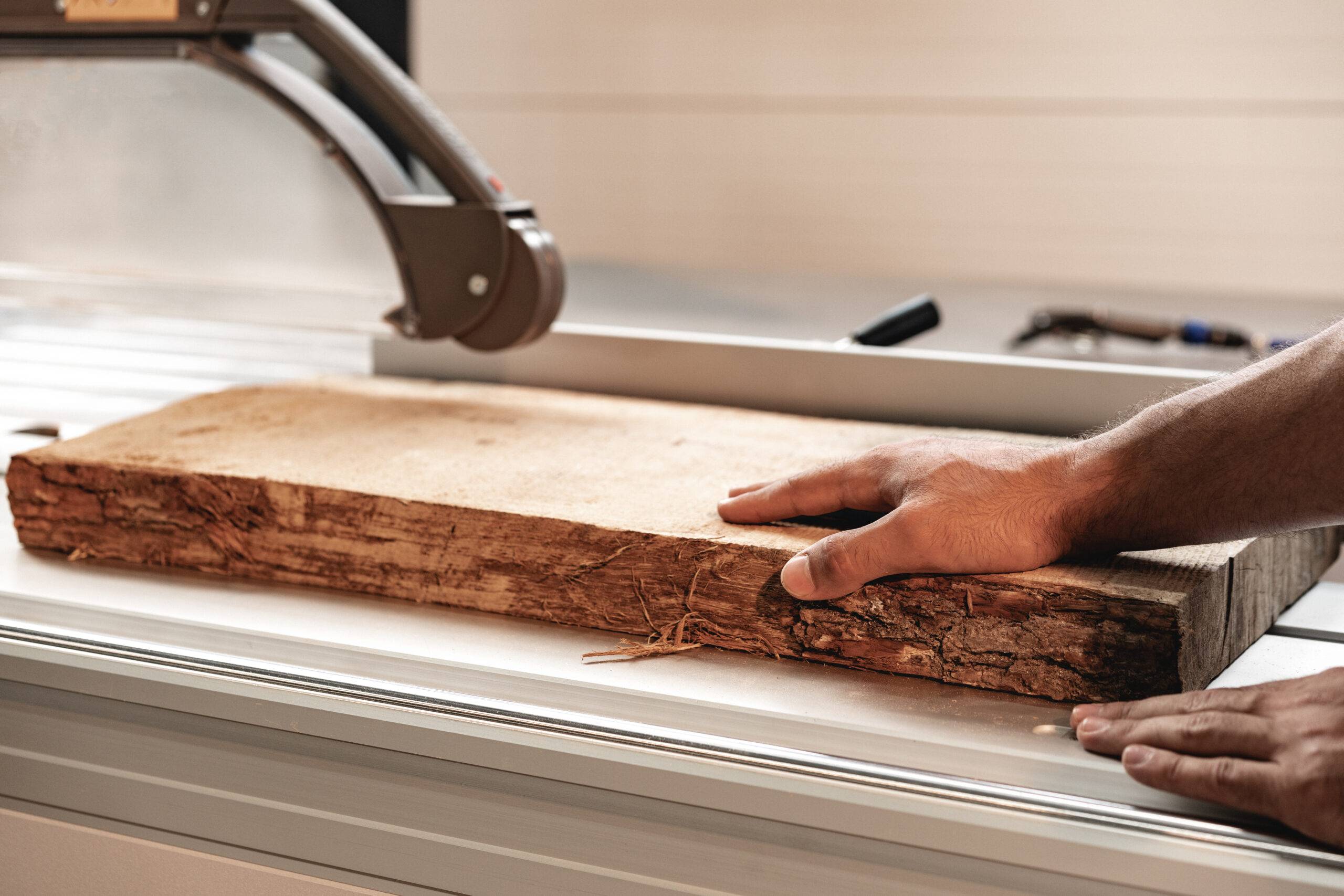 PhotoClose-up photo of carpenter's hands working with wood piece in a workshop