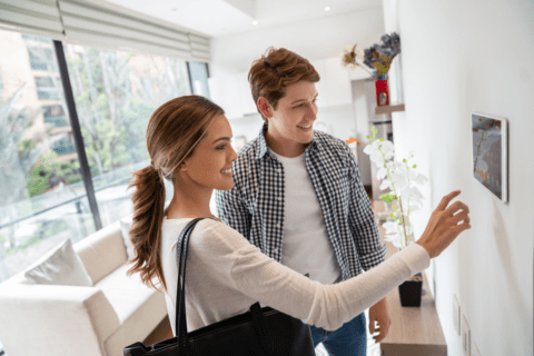 Cheerful young couple activating their smart home security system before leaving