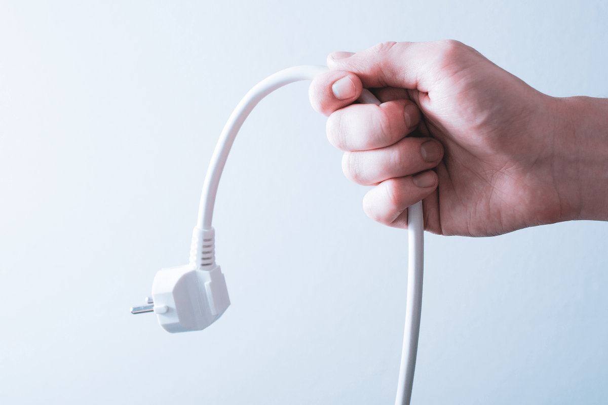 white hand holding a power cable