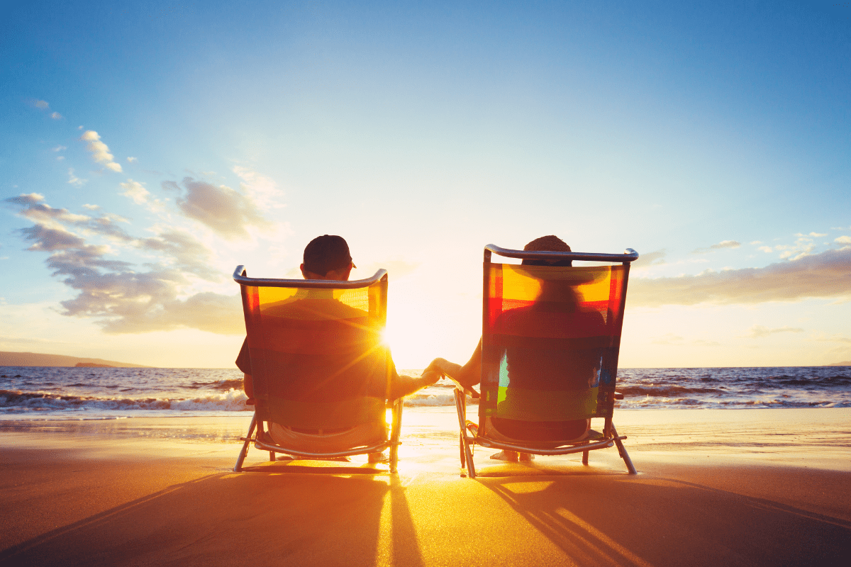 man and woman sitting in beach chairs on the beach watching sunset