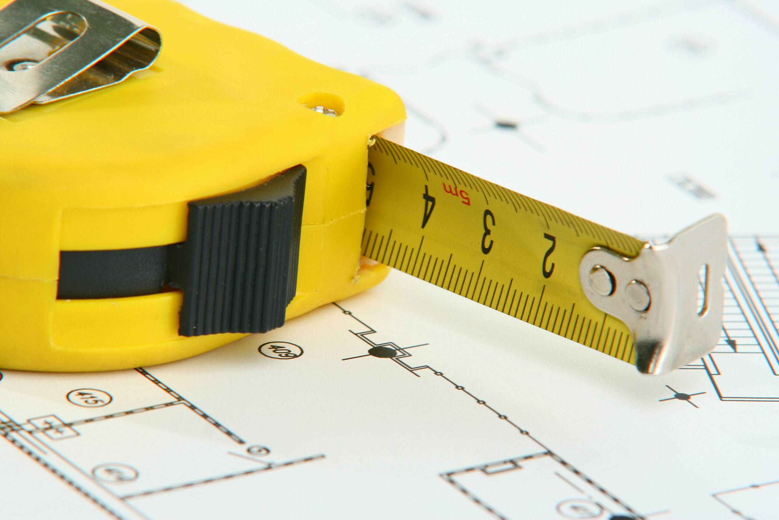 A measuring tape on a blueprint drawing.