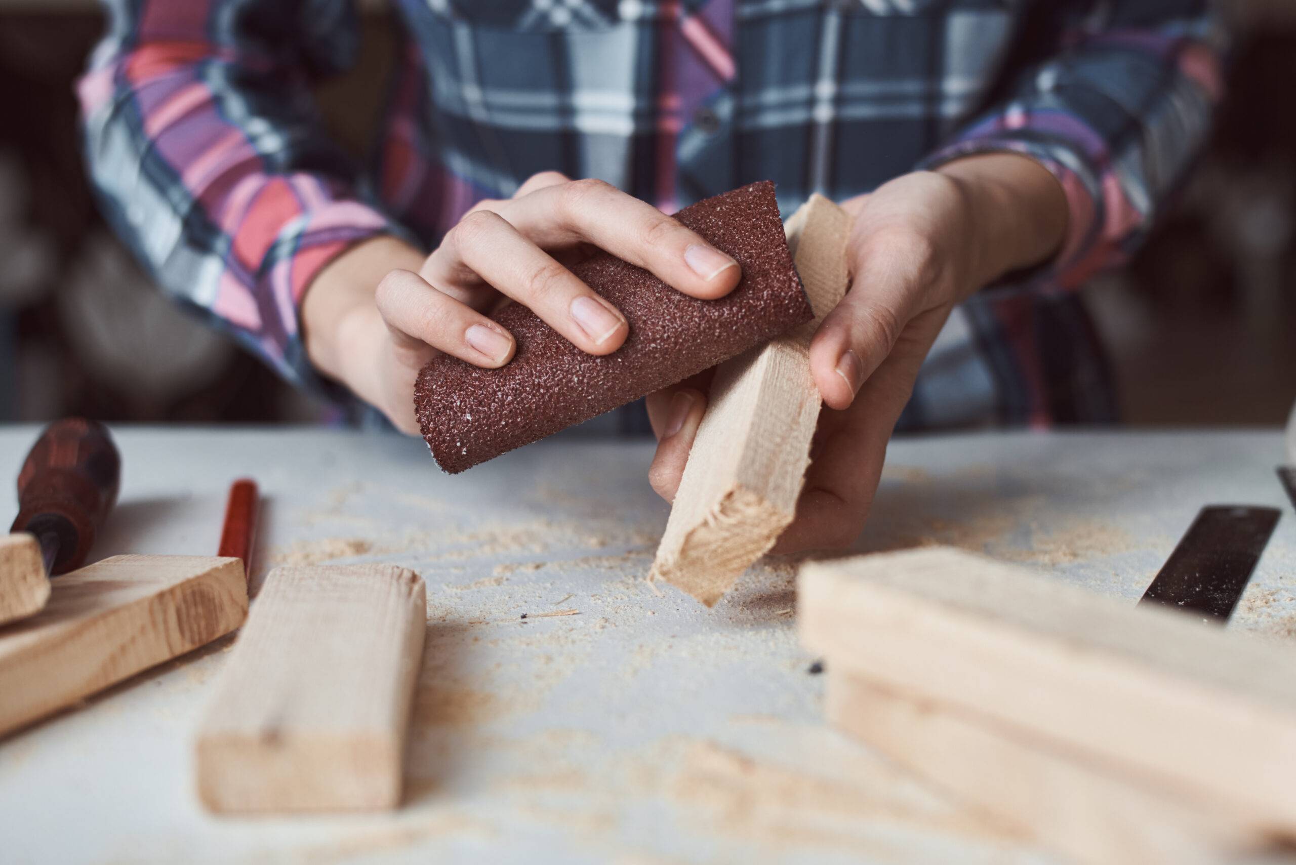 Carpenter hands sanding wooden planks with sandpaper. Concept of DIY woodwork and furniture making