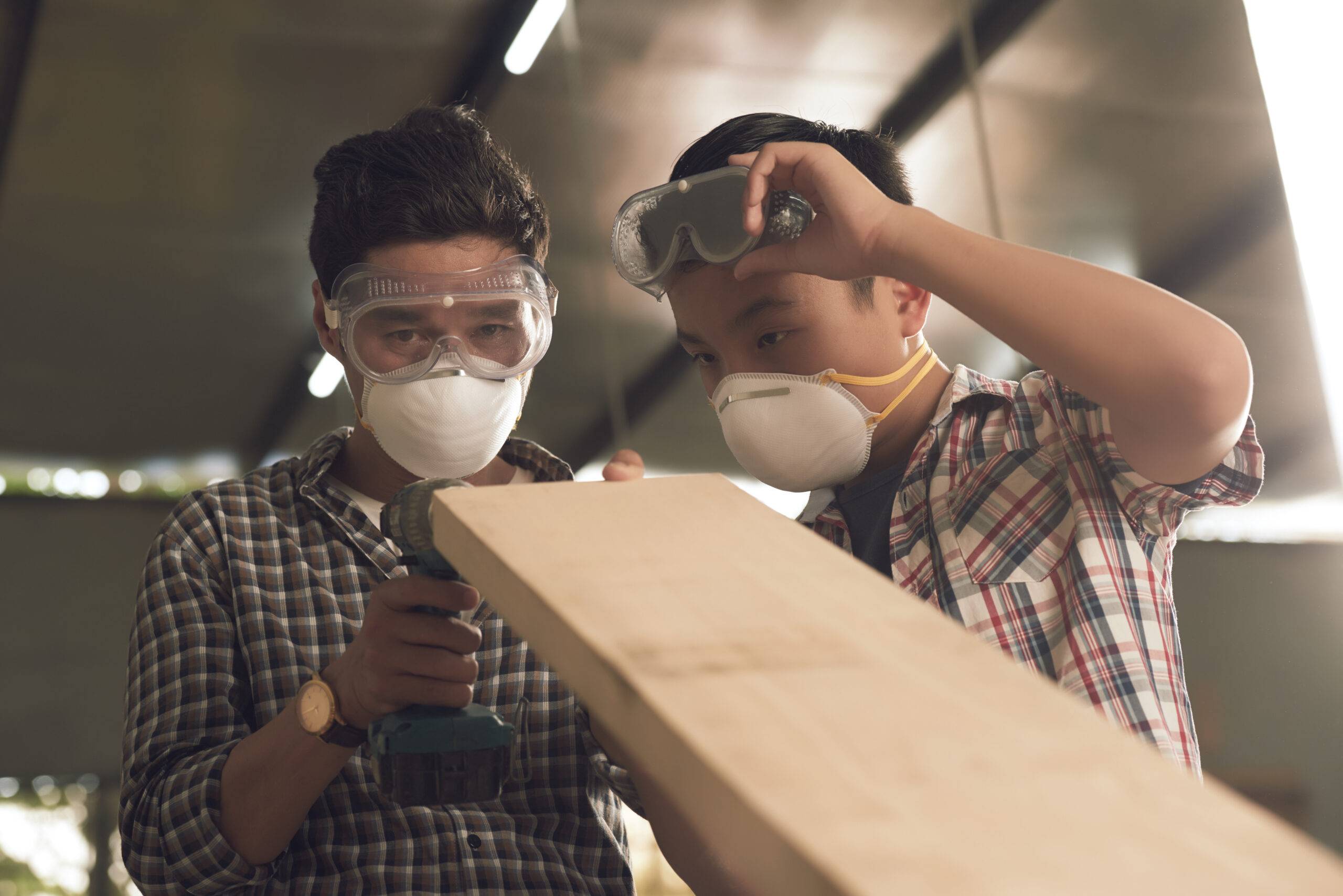 Asian boy and his father checking wooden plank