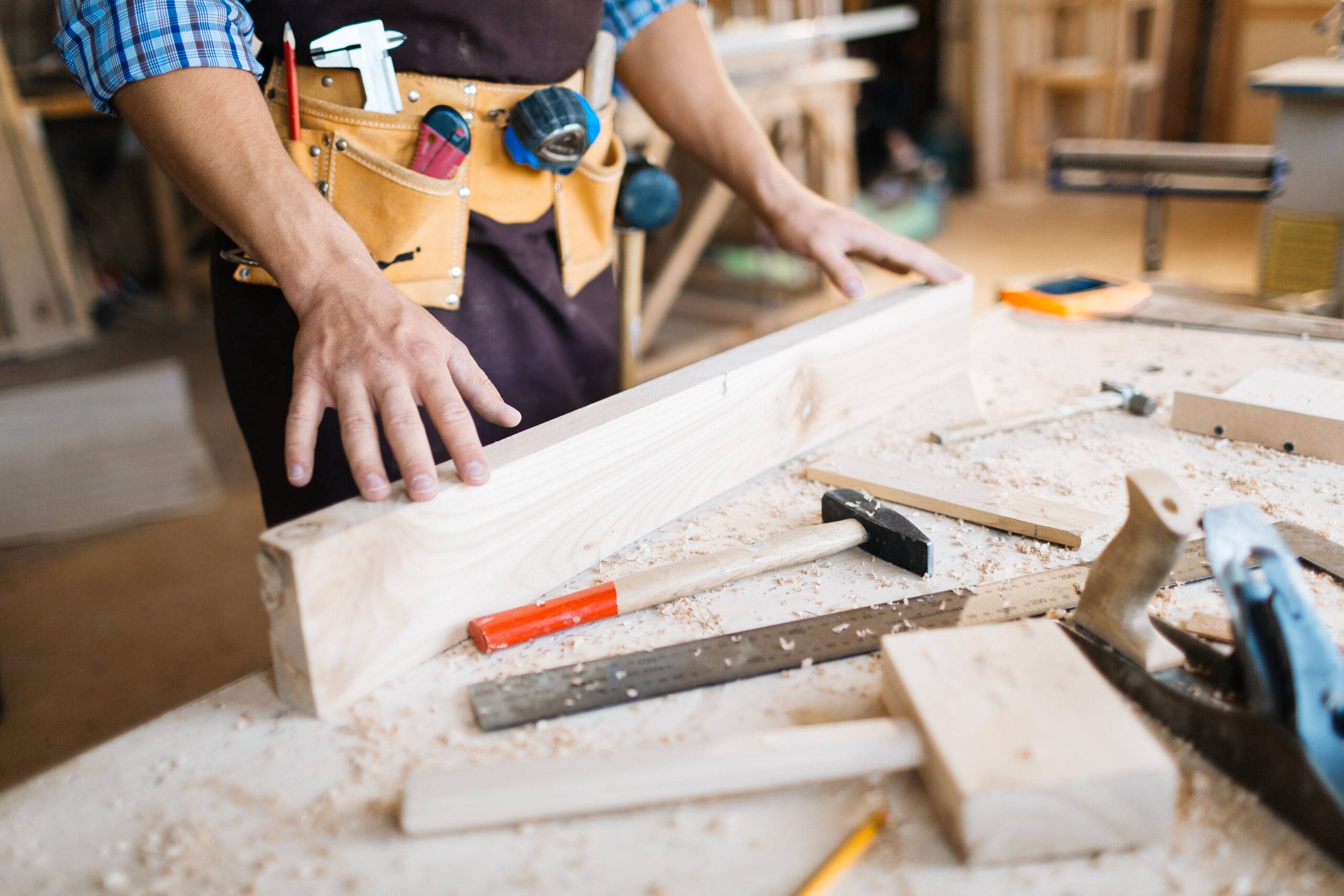 Hands of carpenter on straight wooden plank