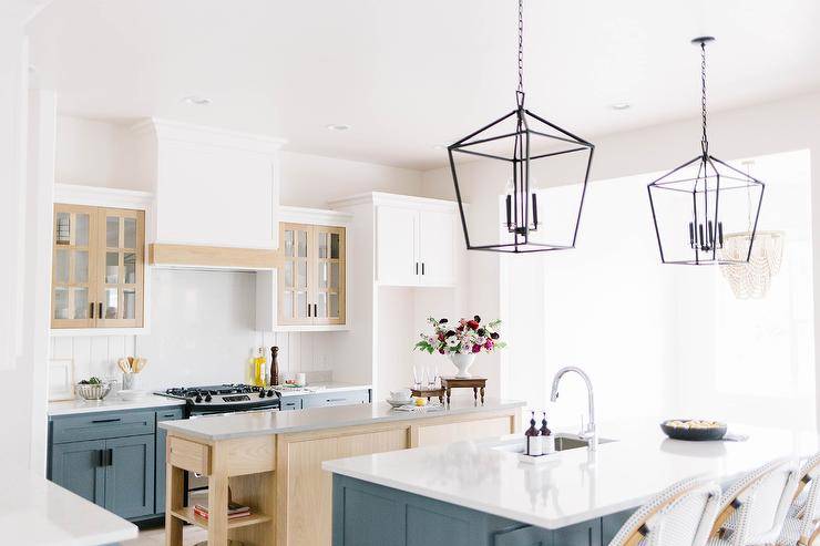 Darlana Lanterns hang over a white quartz countertop accenting a blue kitchen island matched with French bistro stools.