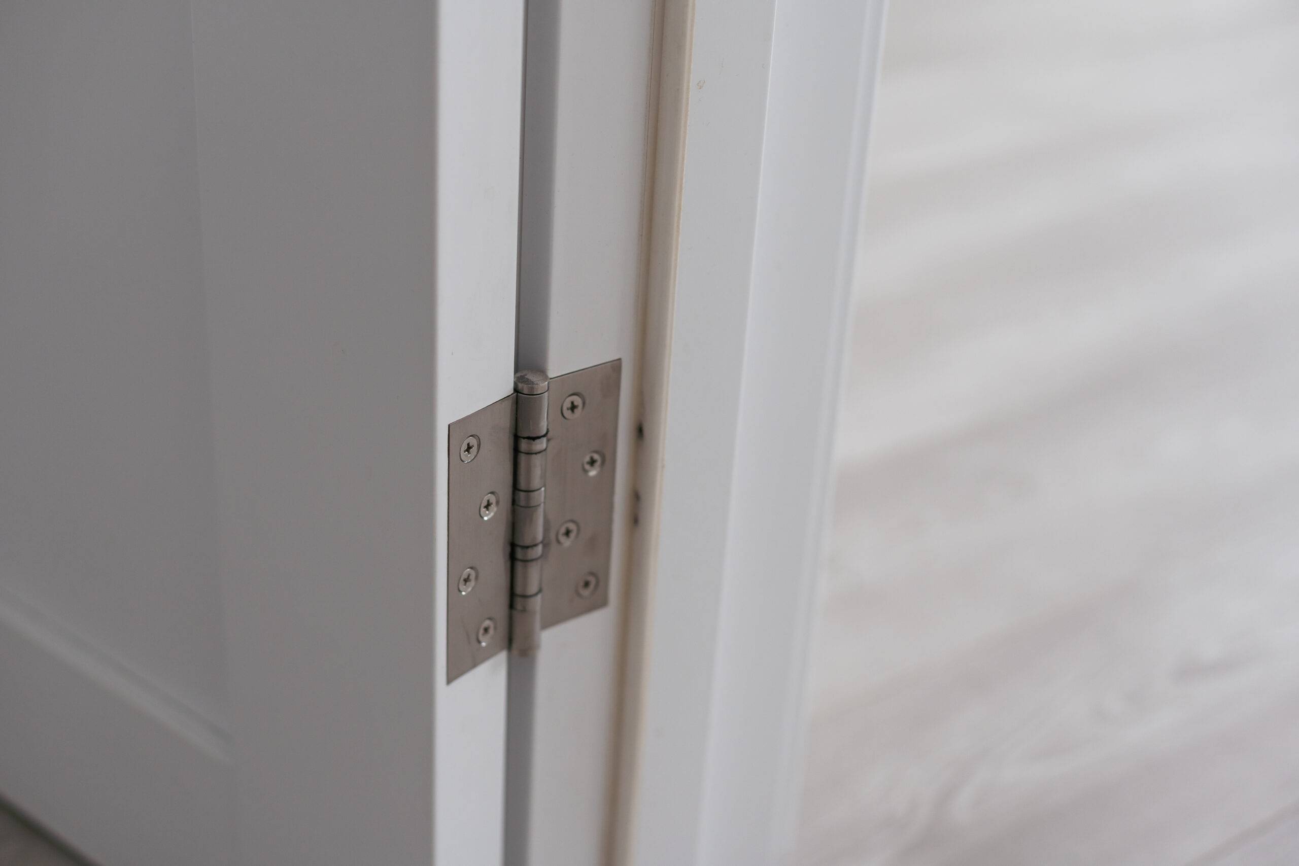 Closeup of a hinge on a white door frame.