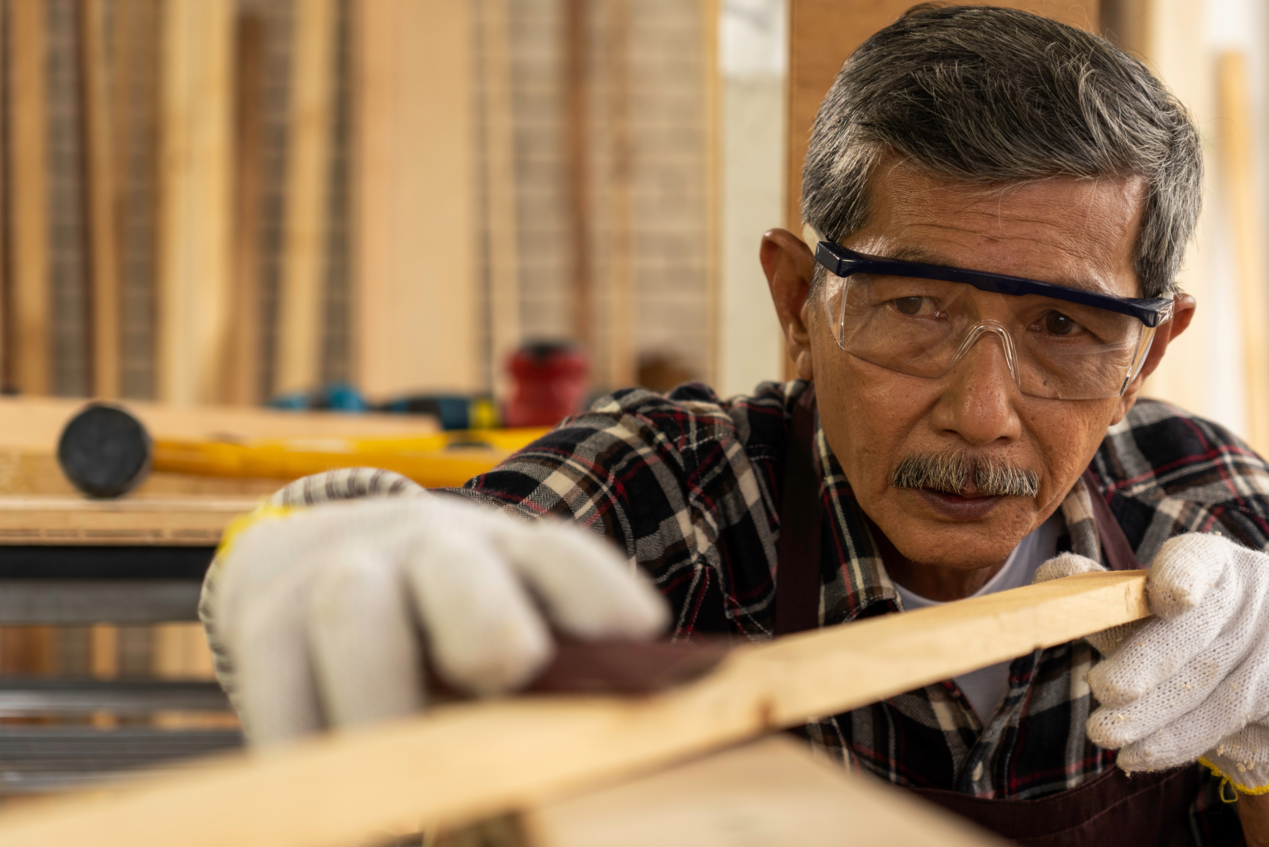 Worker wearing safety glasses and gloves while working with wood