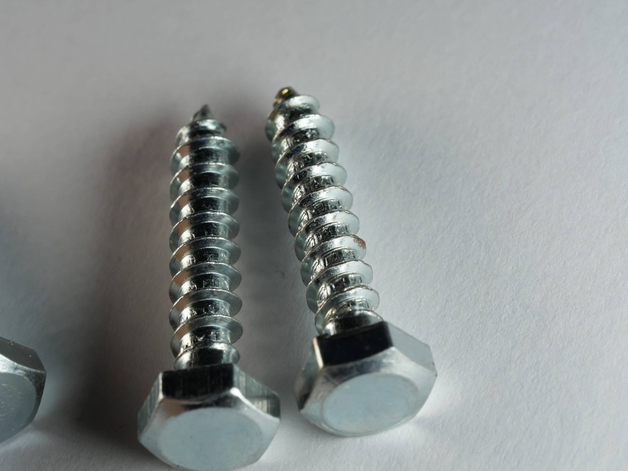 A high angle shot of lag screws on a gray surface.