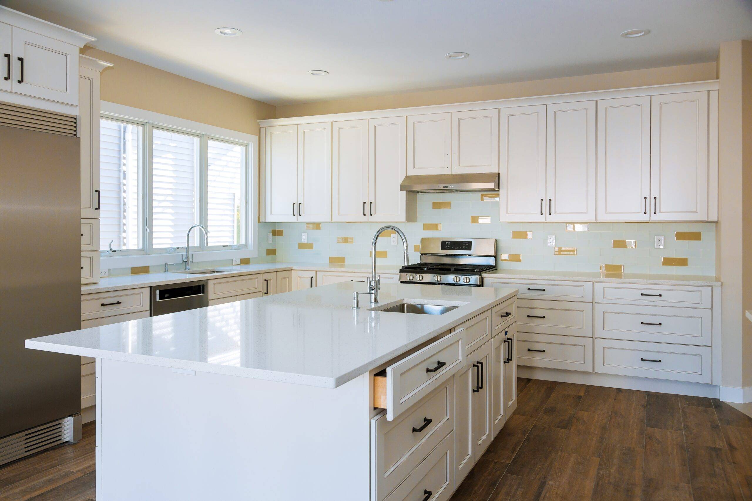 Modern kitchen featuring white cabinets with black handles and a white countertop