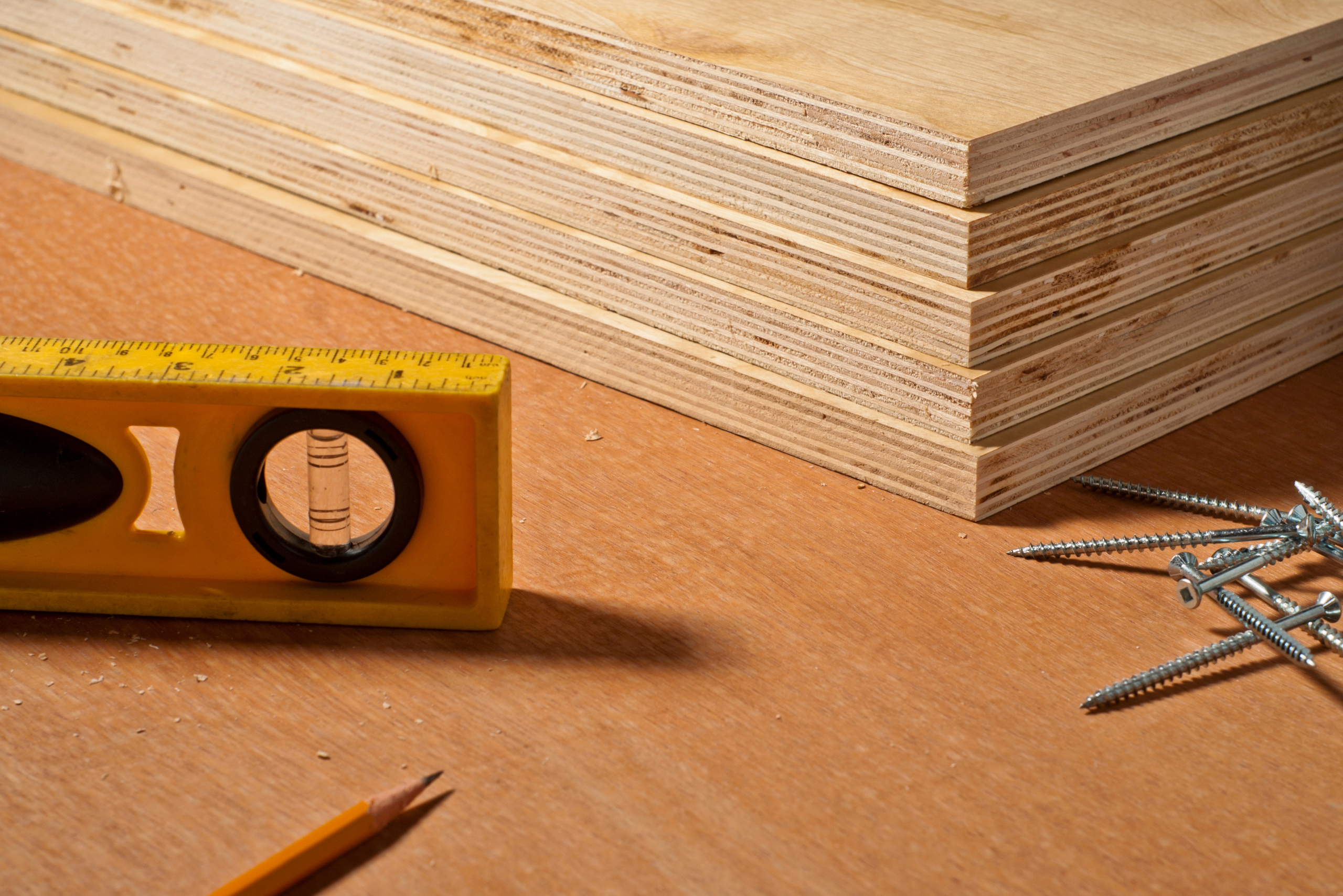A stack of plywood beside a ruler with a built-in level.