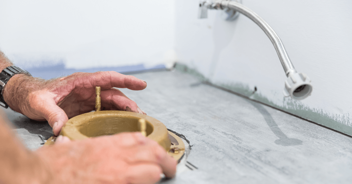 Hands placing toilet wax seal down on flange.