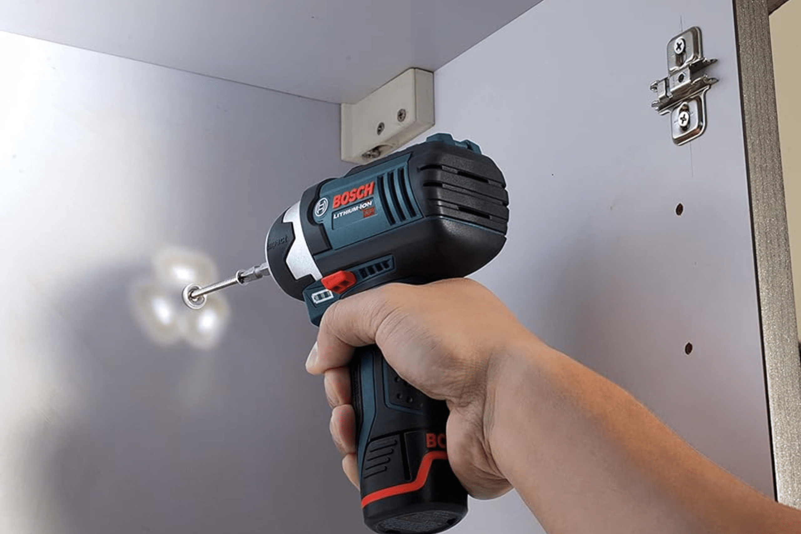 Person using an impact driver to install cabinets.