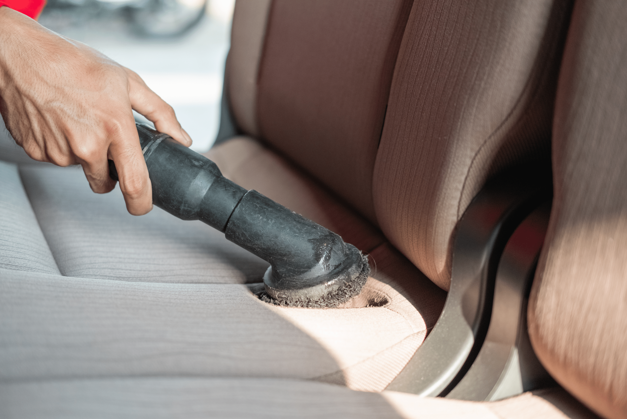 Vacuuming cloth car seats.