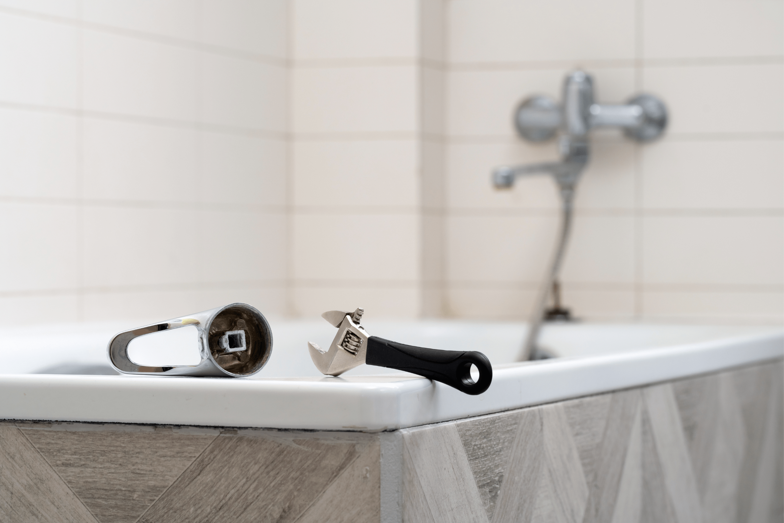 Bathtub with broken handle and an adjustable wrench.