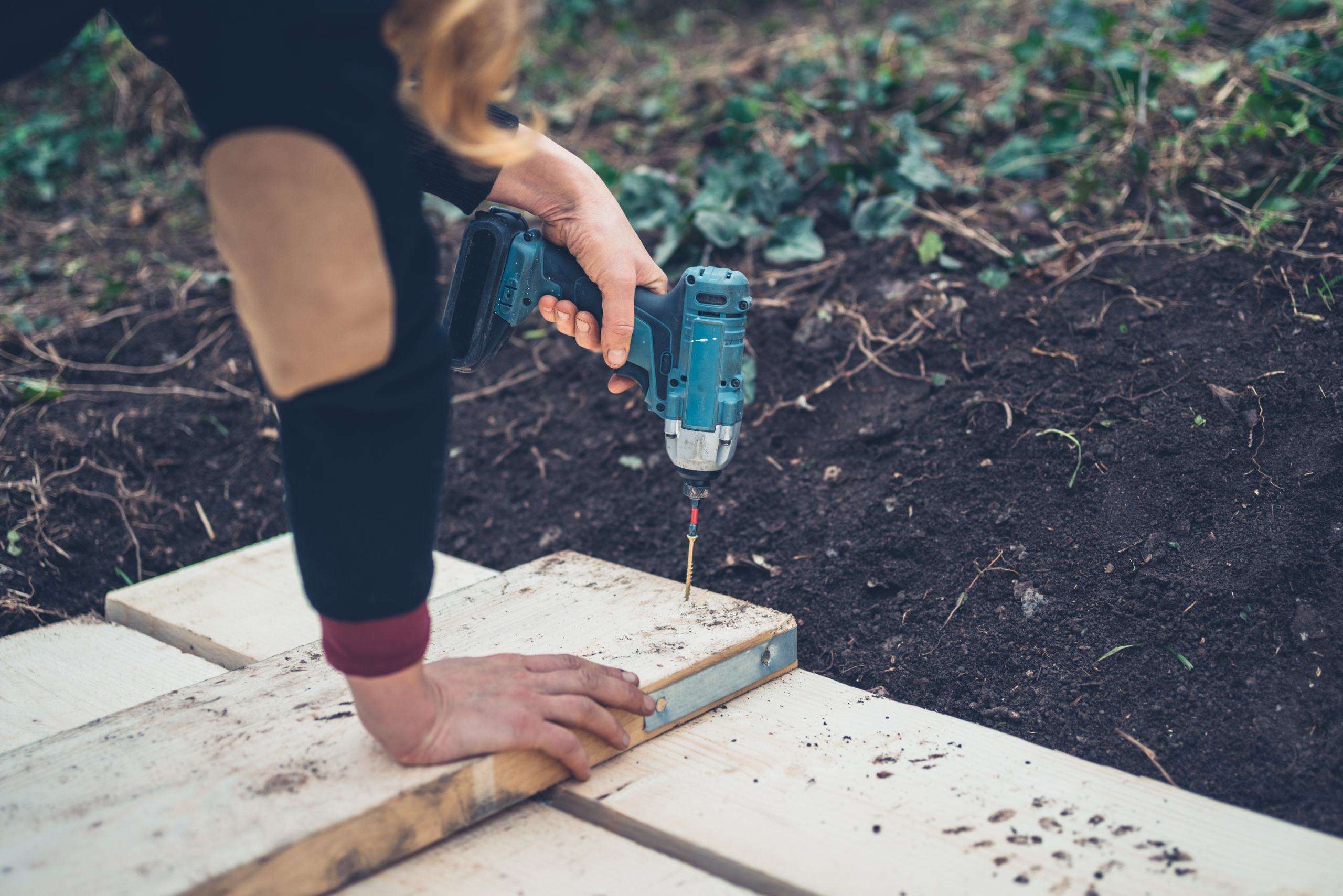 Person using impact driver to drive screws into wood boards.