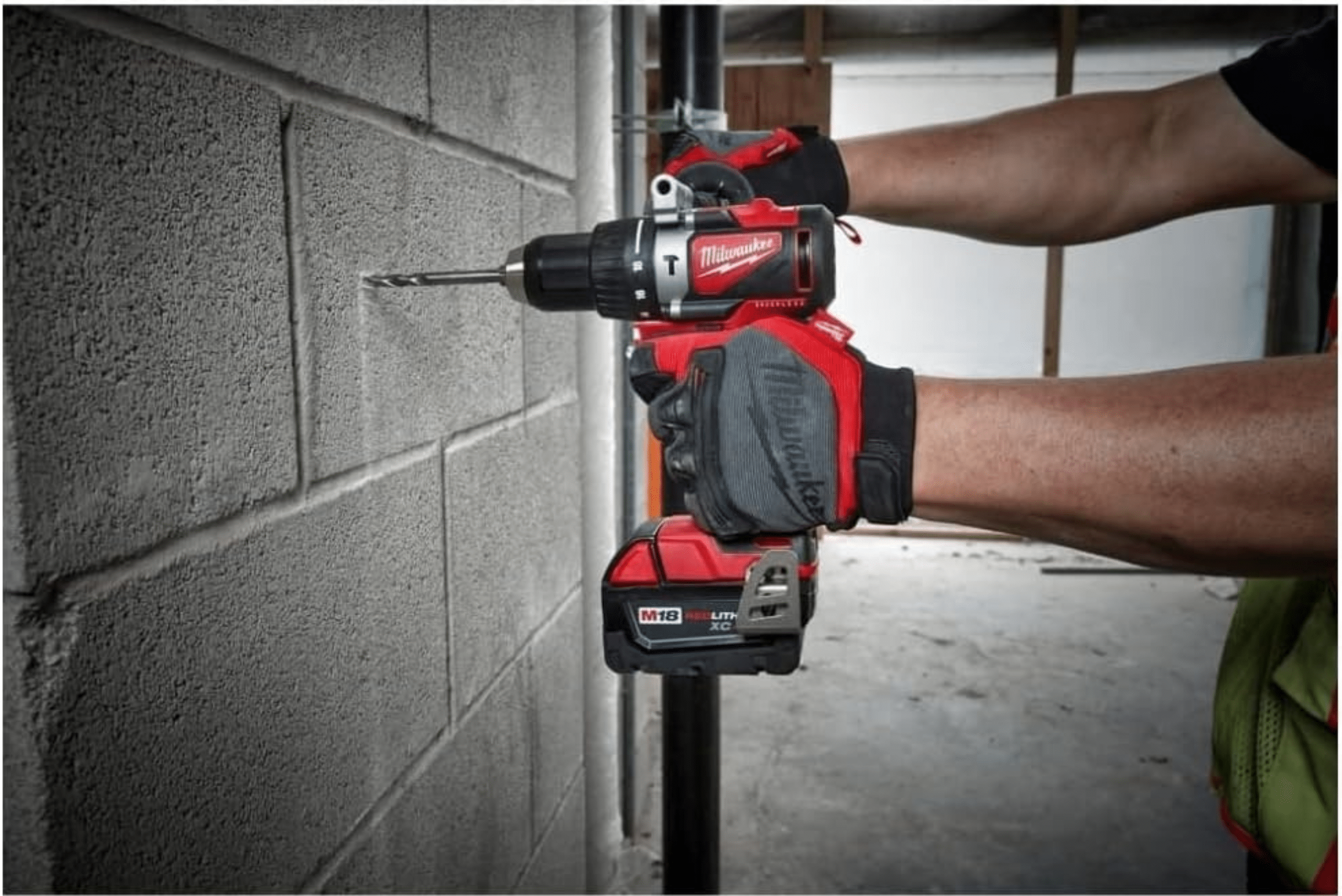 Person using a hammer drill on a wall made of cement blocks.