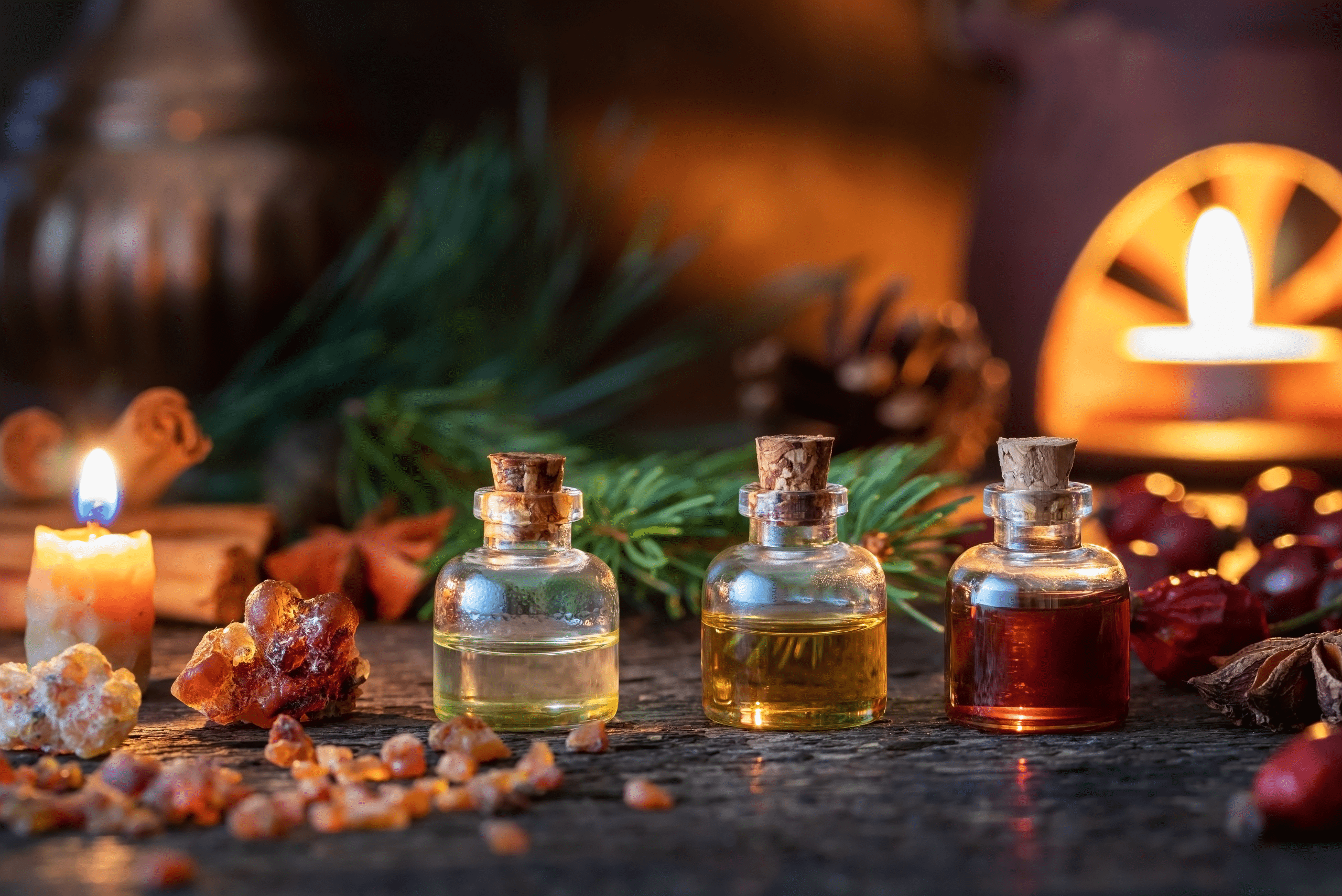 Essential oils in glass bottles beside a lit candle.