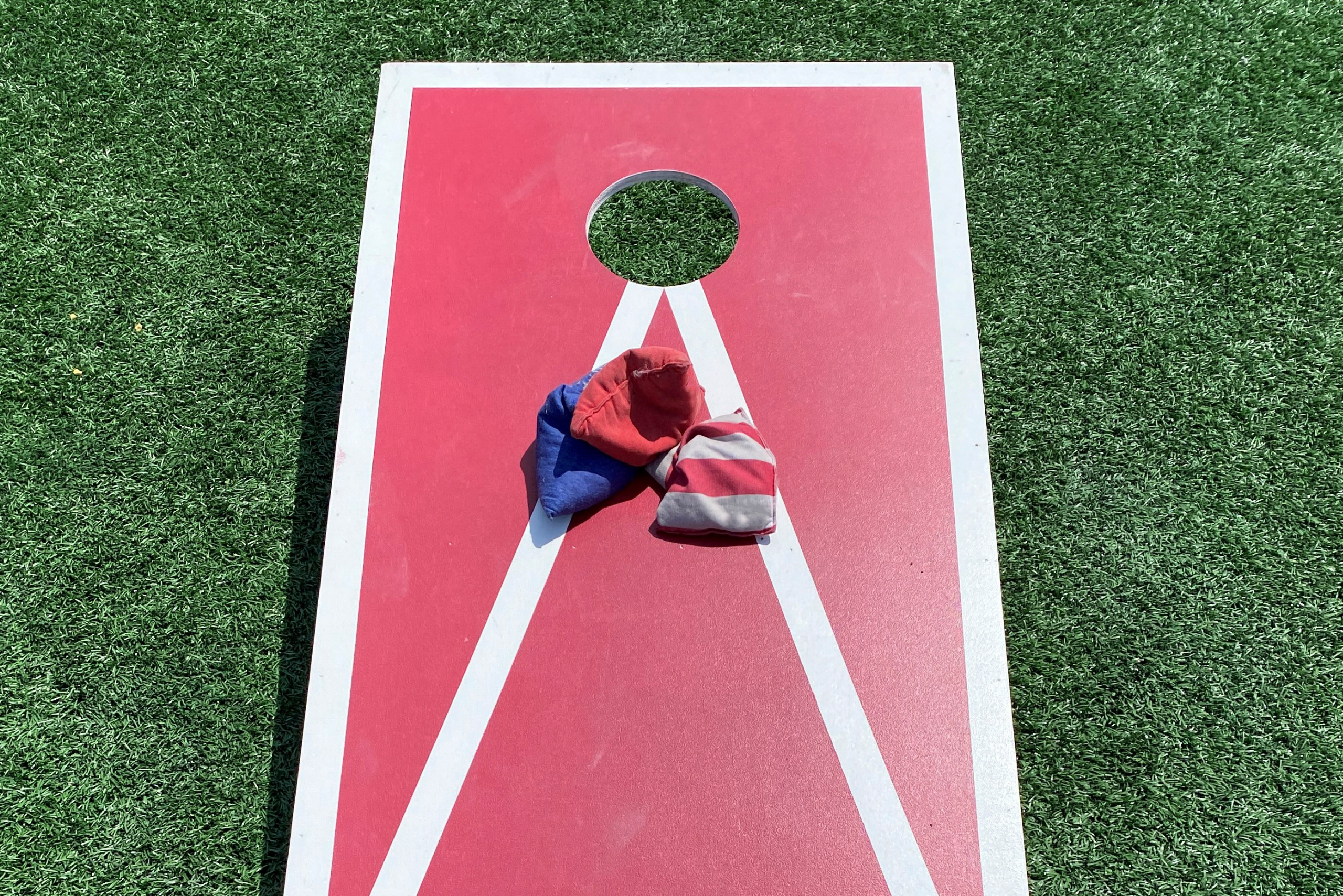 Red cornhole board with playing bags on top.