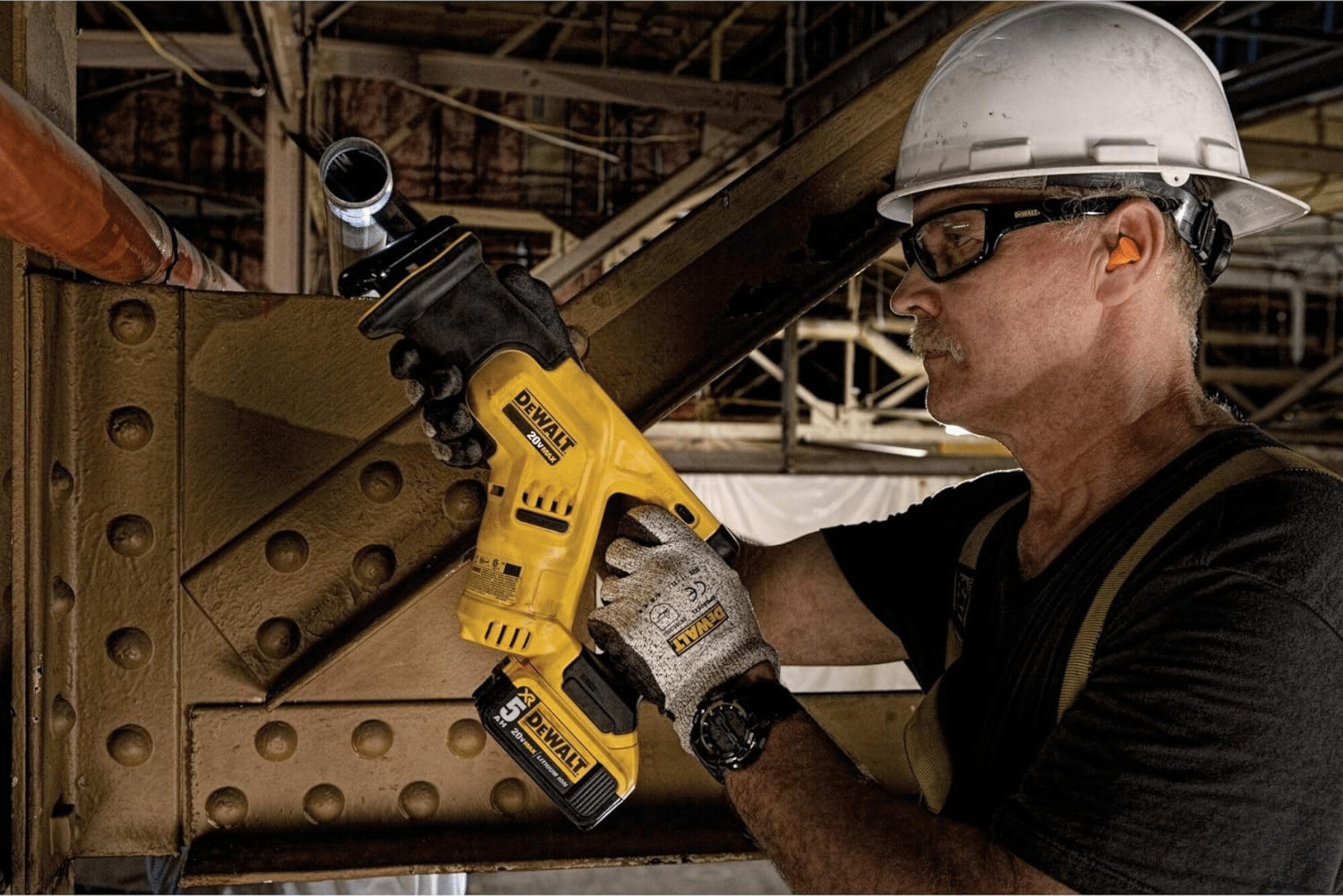 Worker using a reciprocating saw to cut piping.