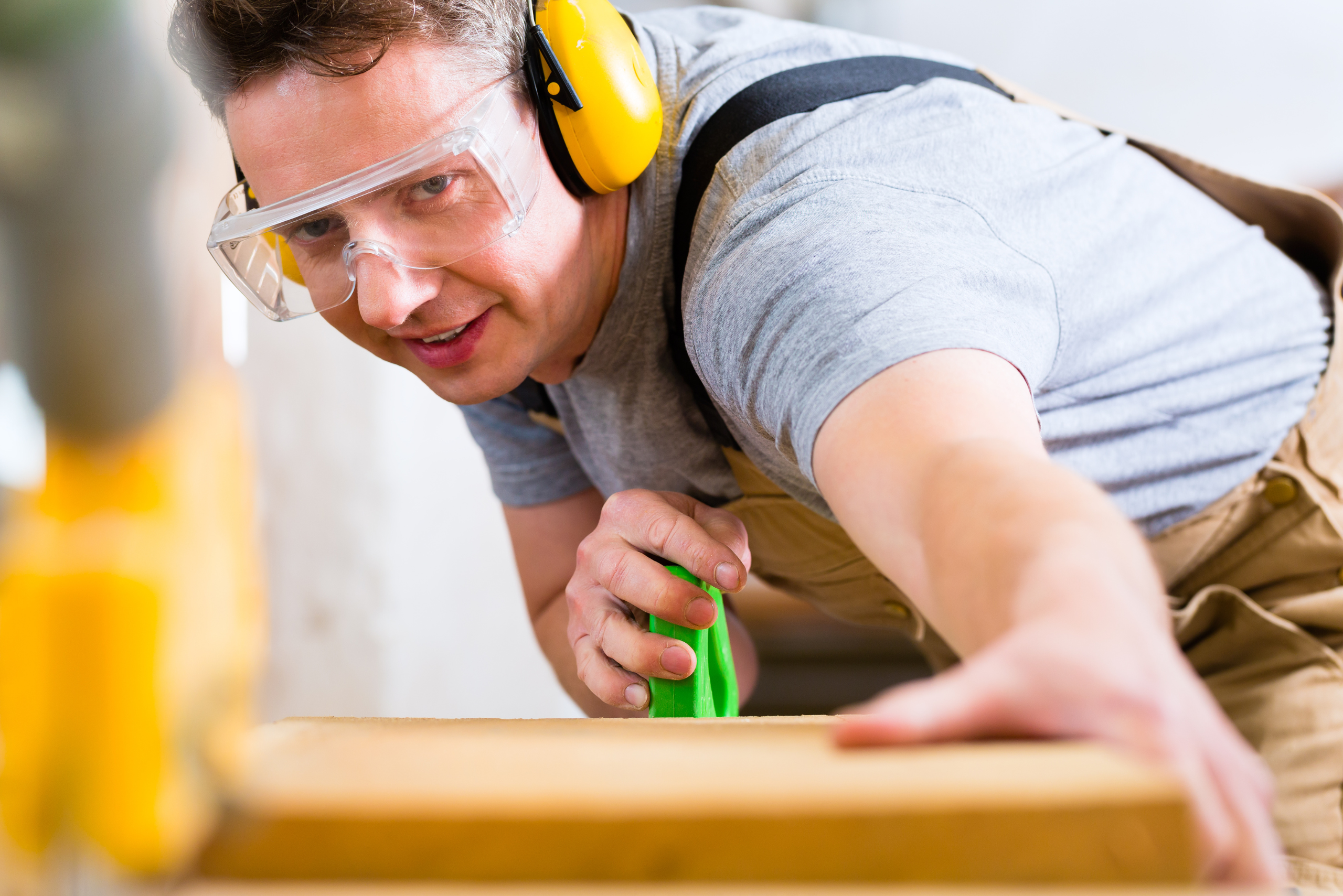 Person wearing safety gear while cutting wood.