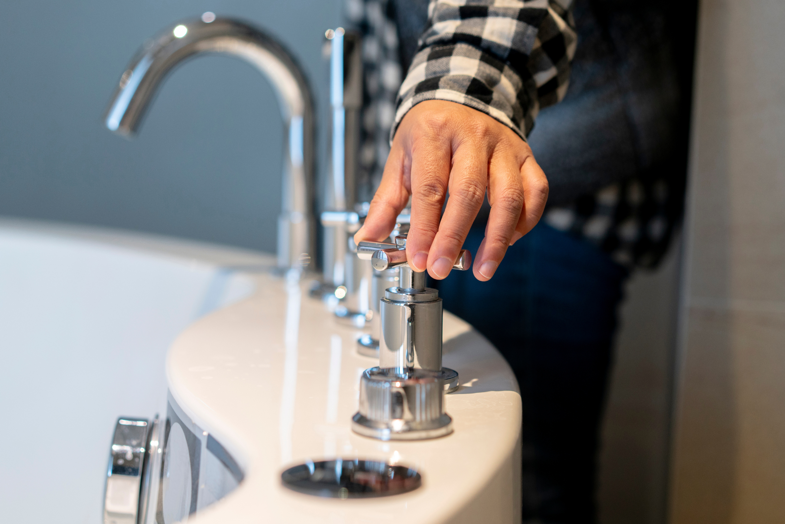 Person turning water knob for bathtub.