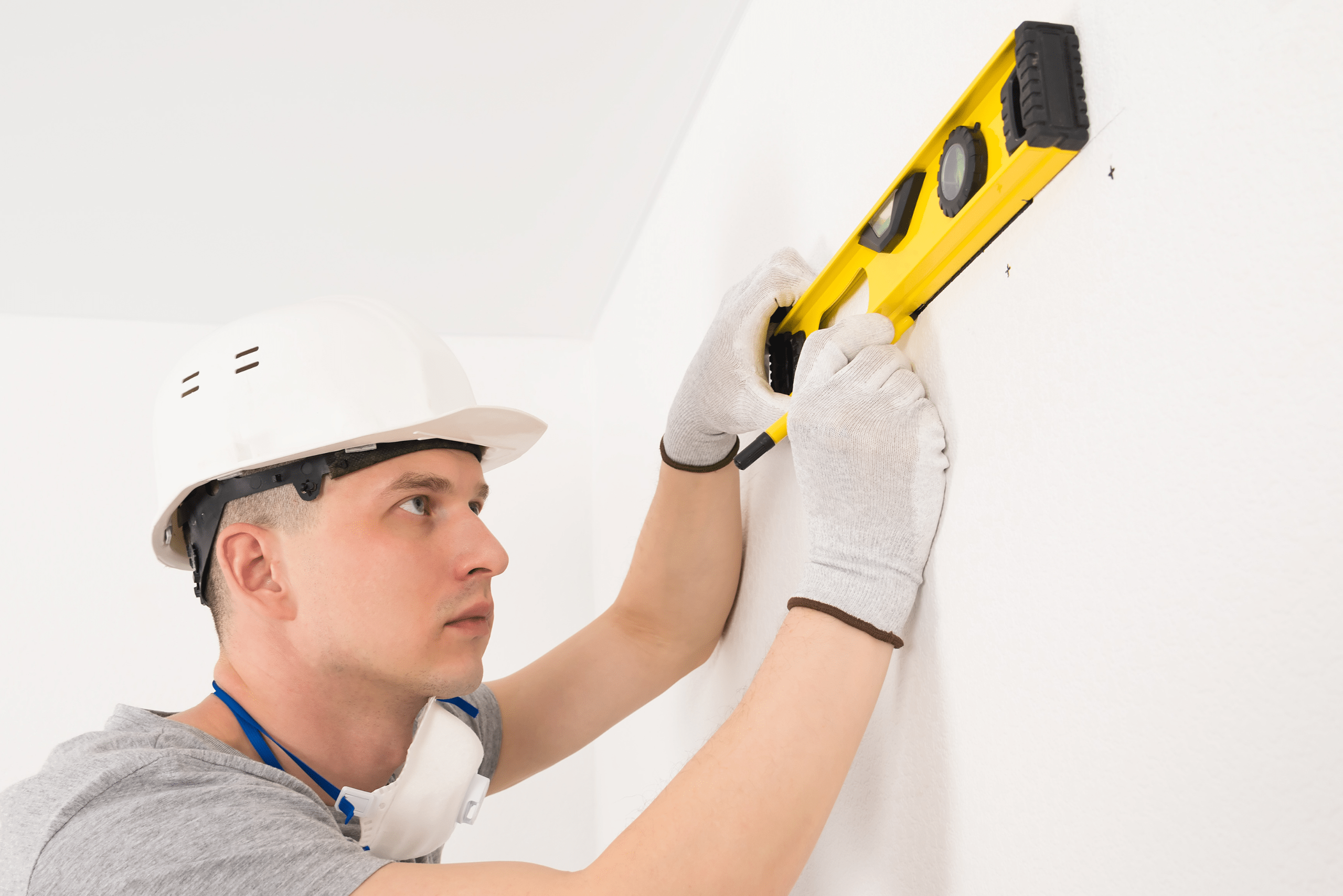 Worker using level to place marks for where to use drywall anchors.