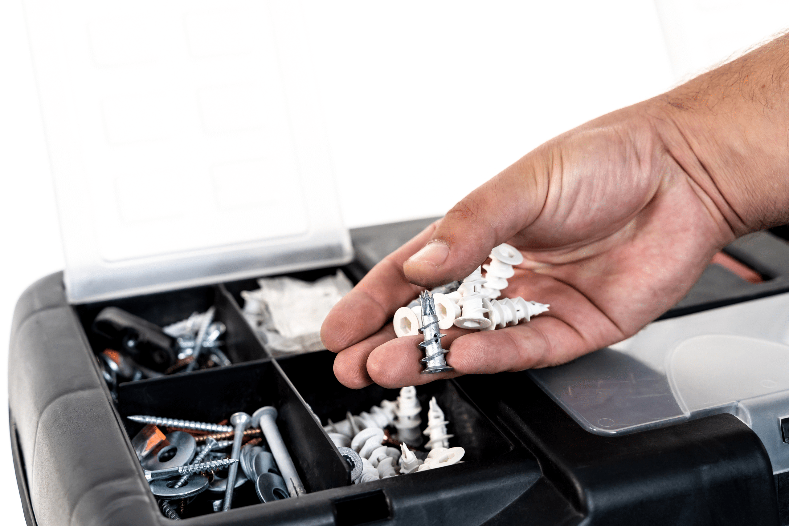 Hand holding a bunch of drywall anchors from a tool box.