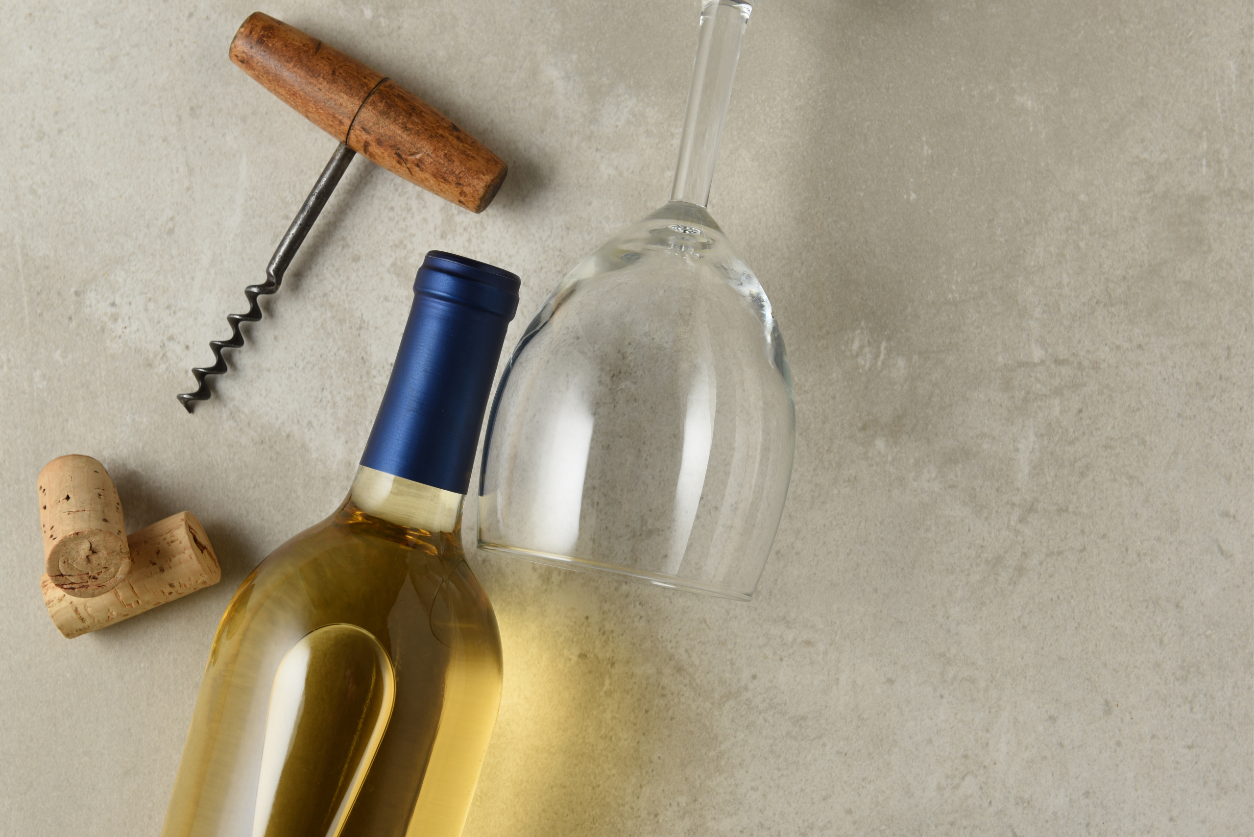 Wine bottle laid near corkscrew and wine glass.