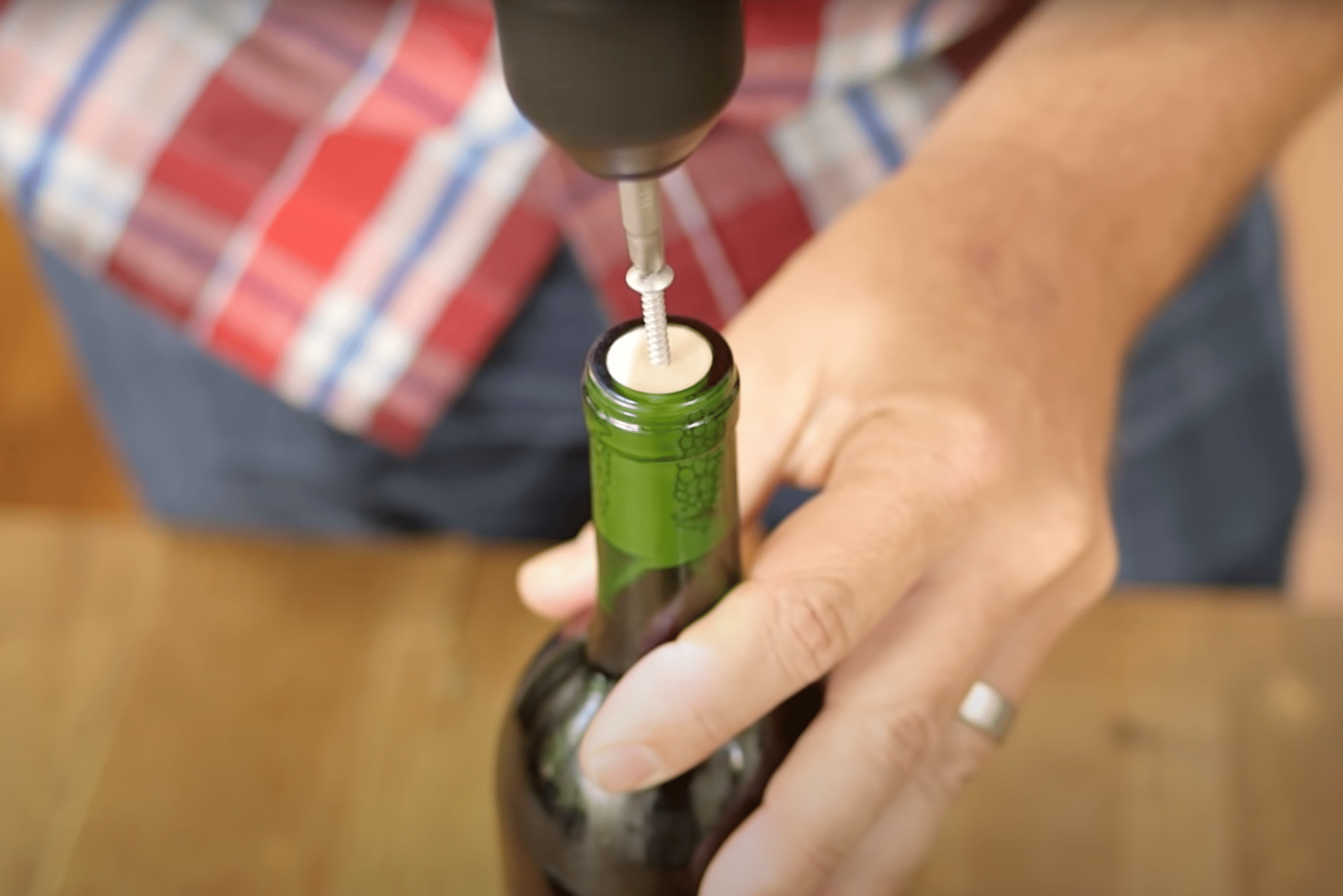 Person using a screw to open wine bottle.