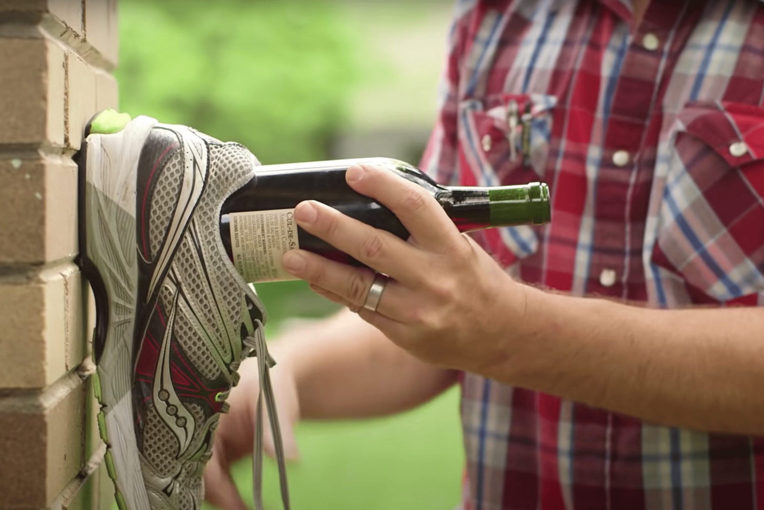Person using shoe to open wine bottle.